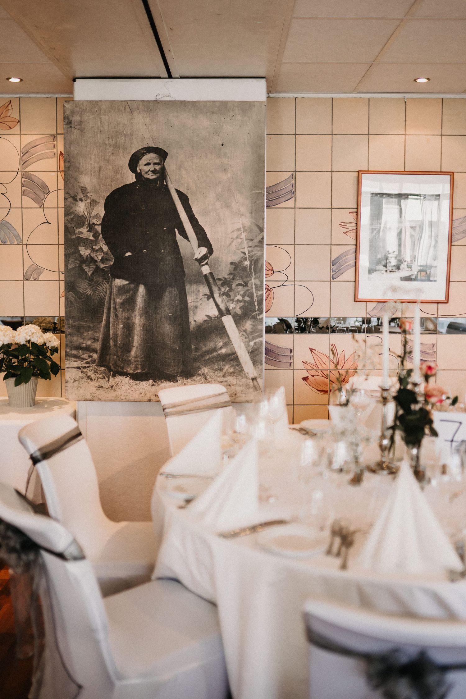 Elegant wedding reception venue with white-clothed tables and vintage wall decorations.