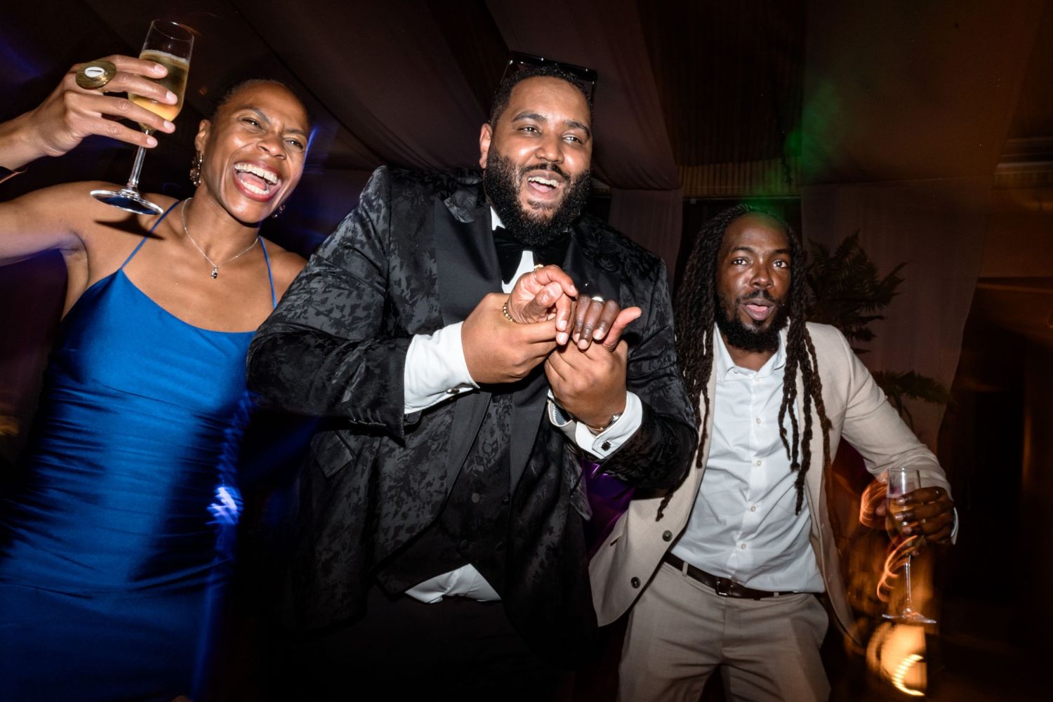 Party guests celebrating with drinks and laughter at nighttime reception.
