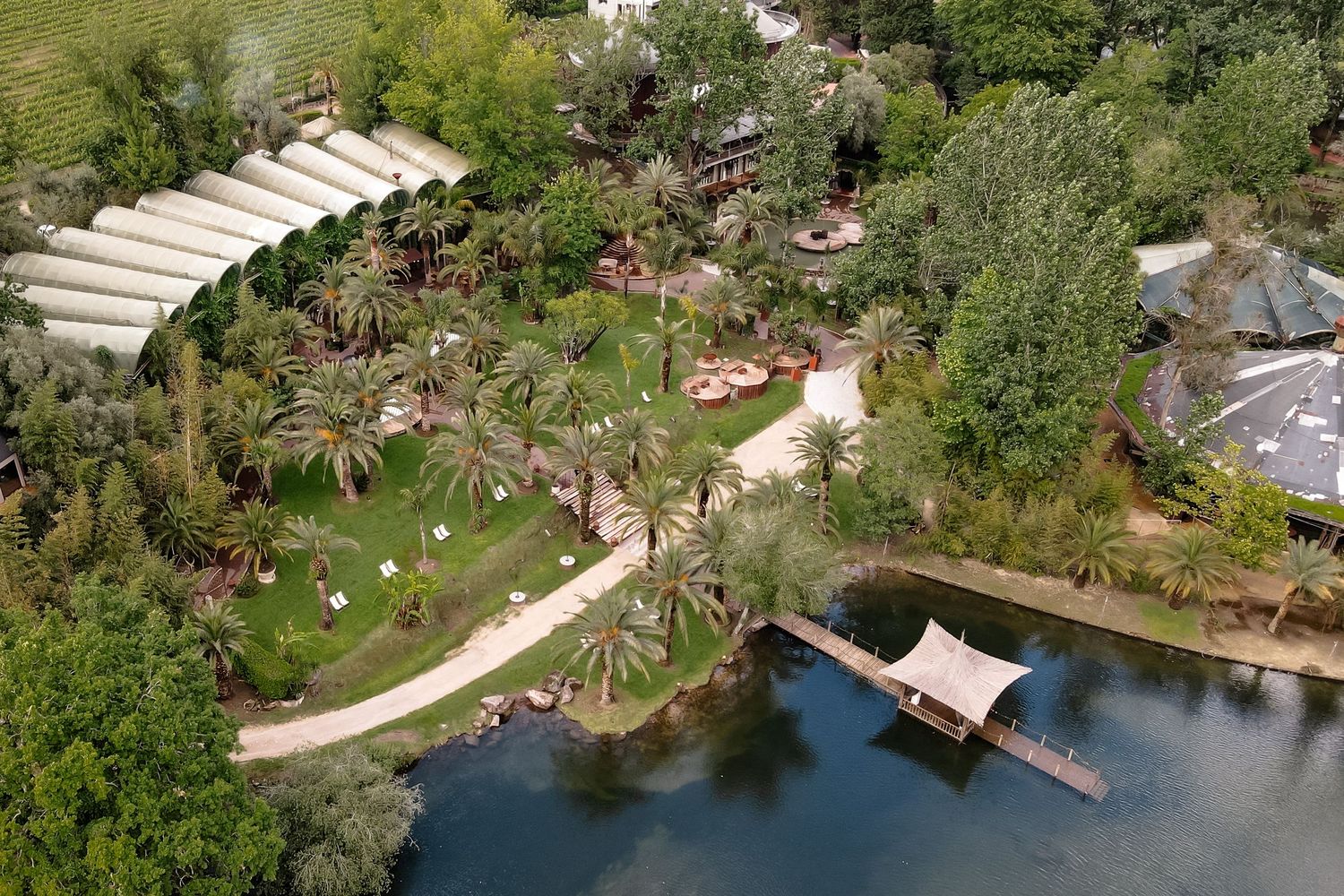 Aerial view of a lush garden landscape with winding paths and water features surrounded by greenery.