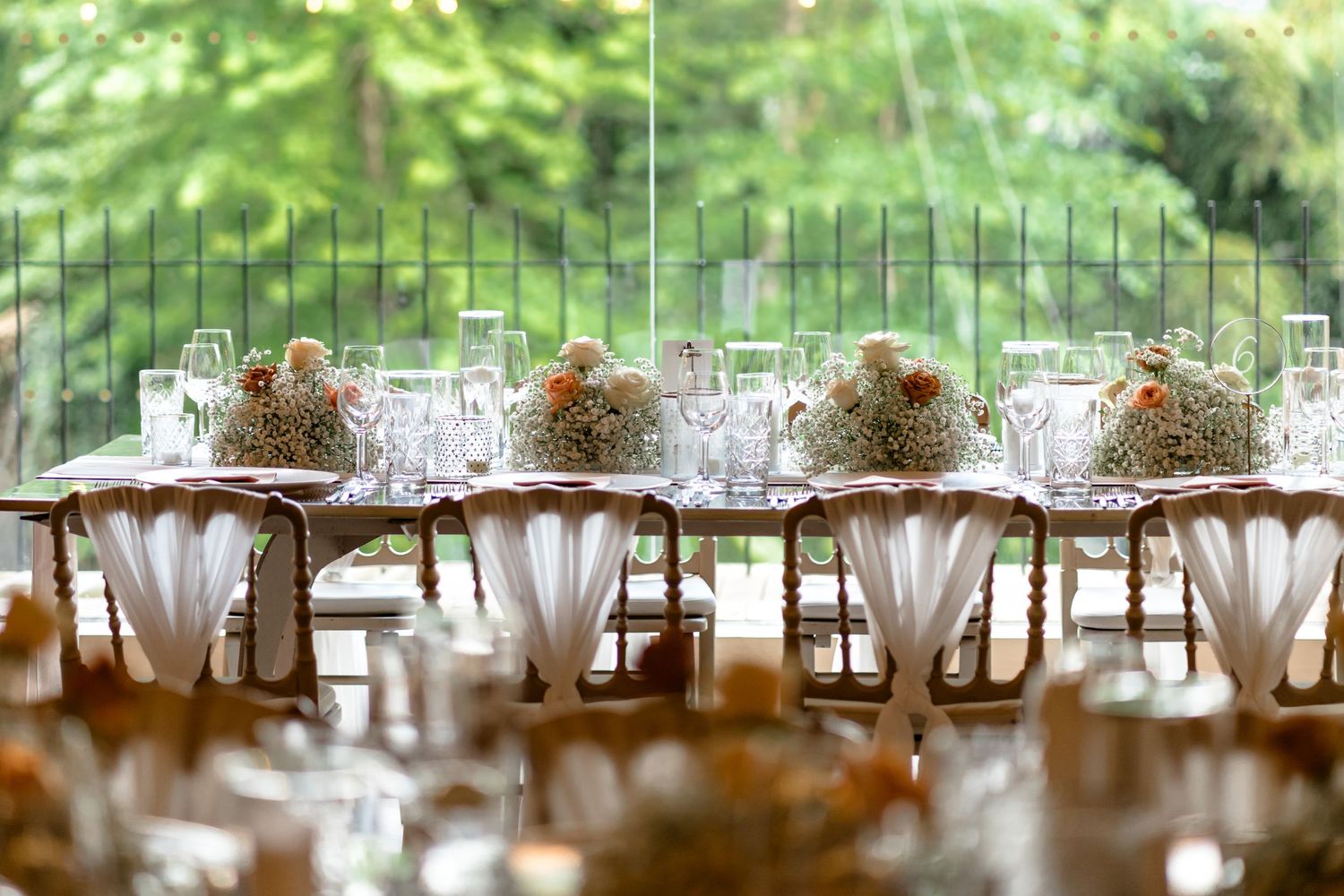 Wedding reception tables set with delicate china and floral centerpieces.