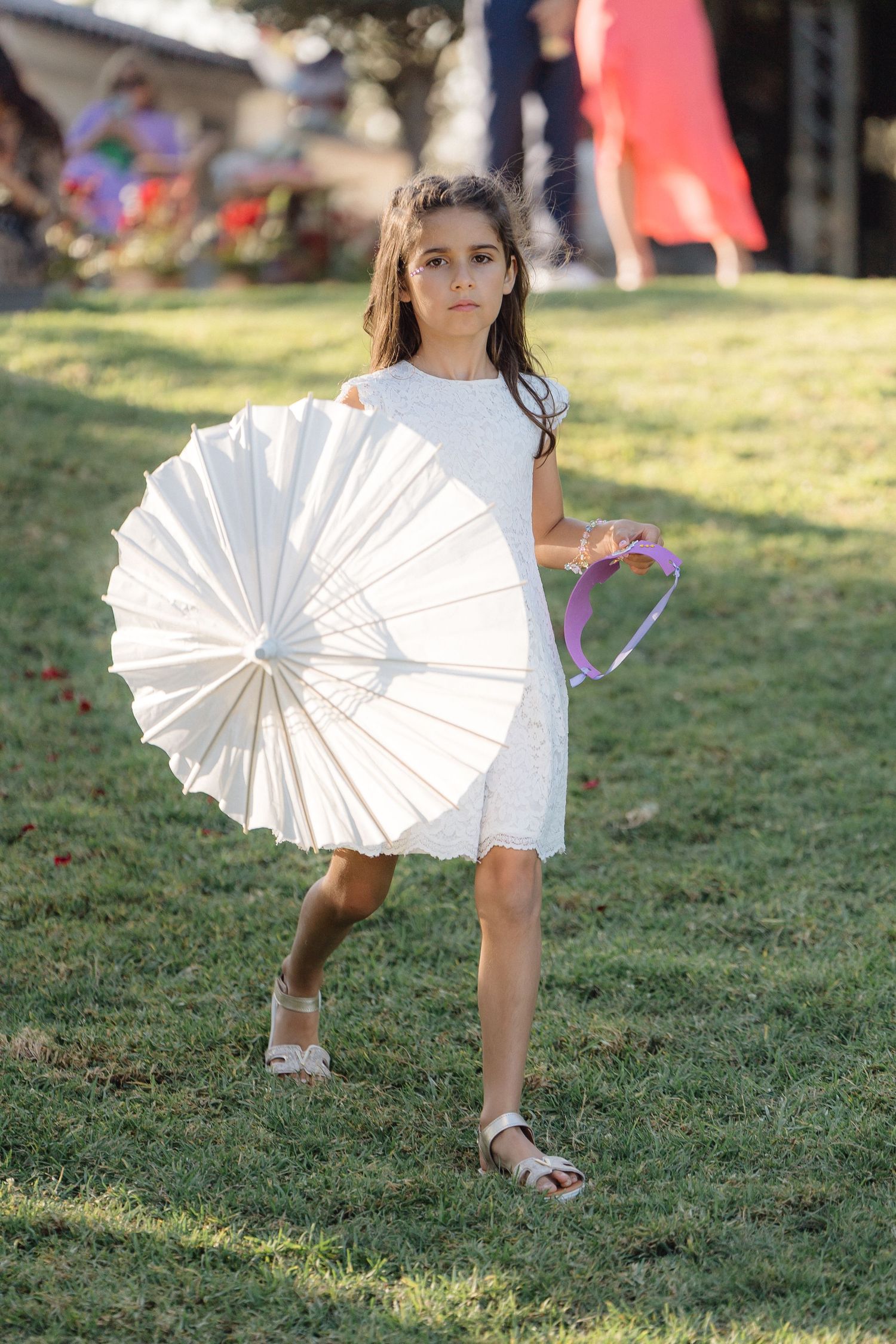 A child plays with a white paper parasol on a grassy lawn.