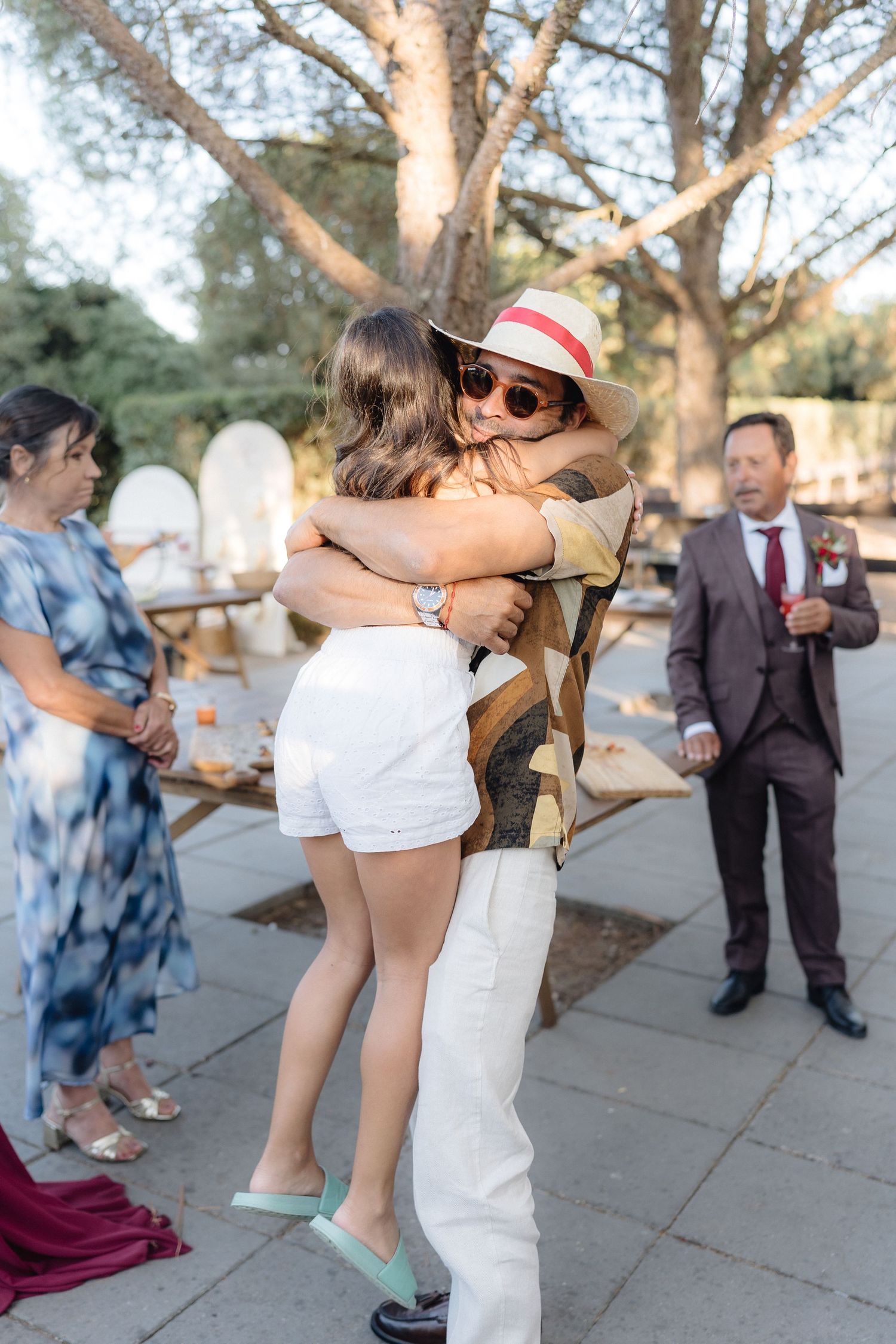 Guests dancing and celebrating at an outdoor wedding reception with trees in the background.