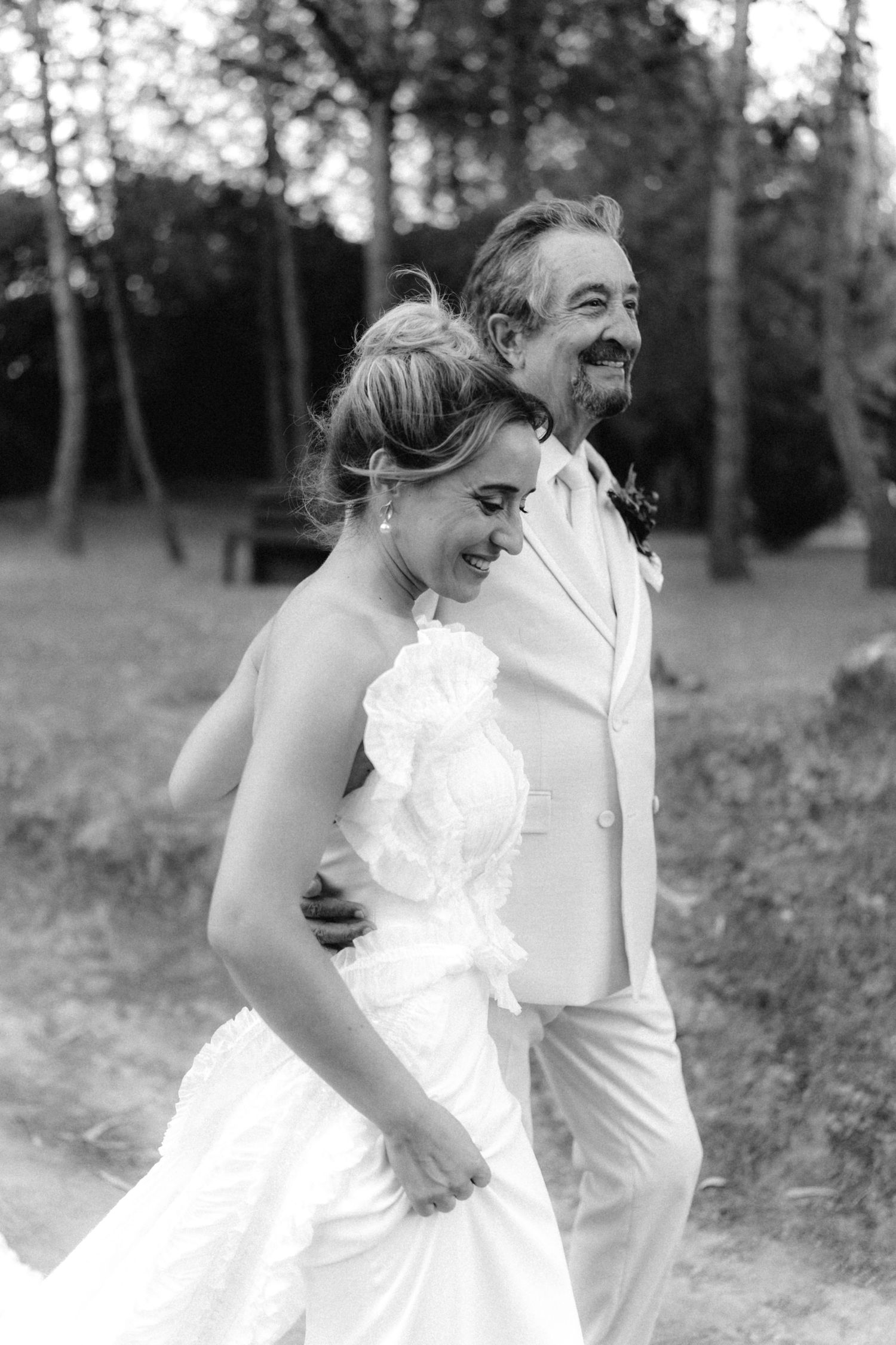 Black and white photo of a couple laughing together during their outdoor wedding shoot.