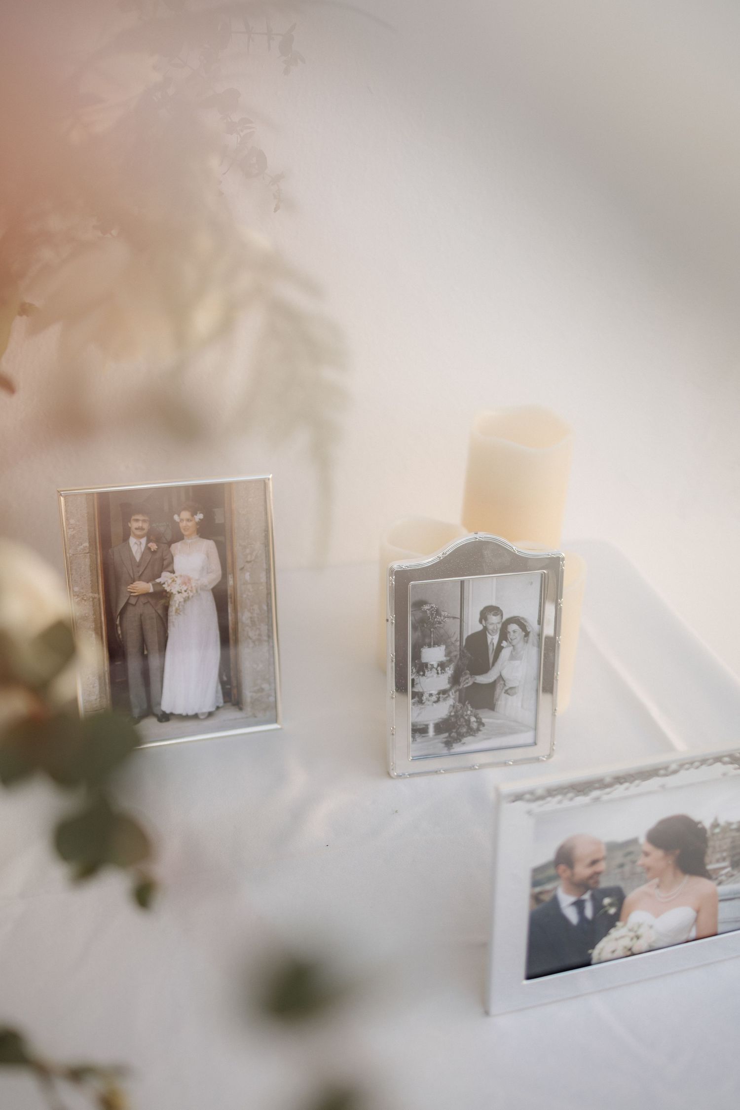 Vintage black and white photographs displayed on a white wall in silver frames.