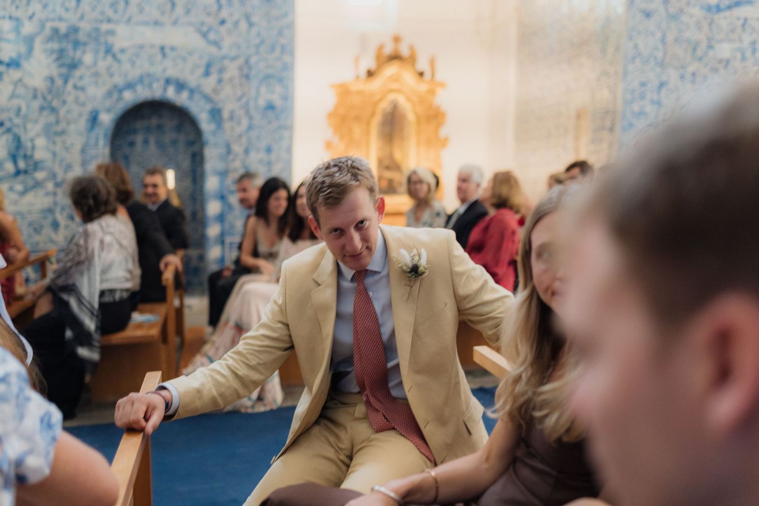 Wedding guests seated in wooden pews during an indoor church ceremony.