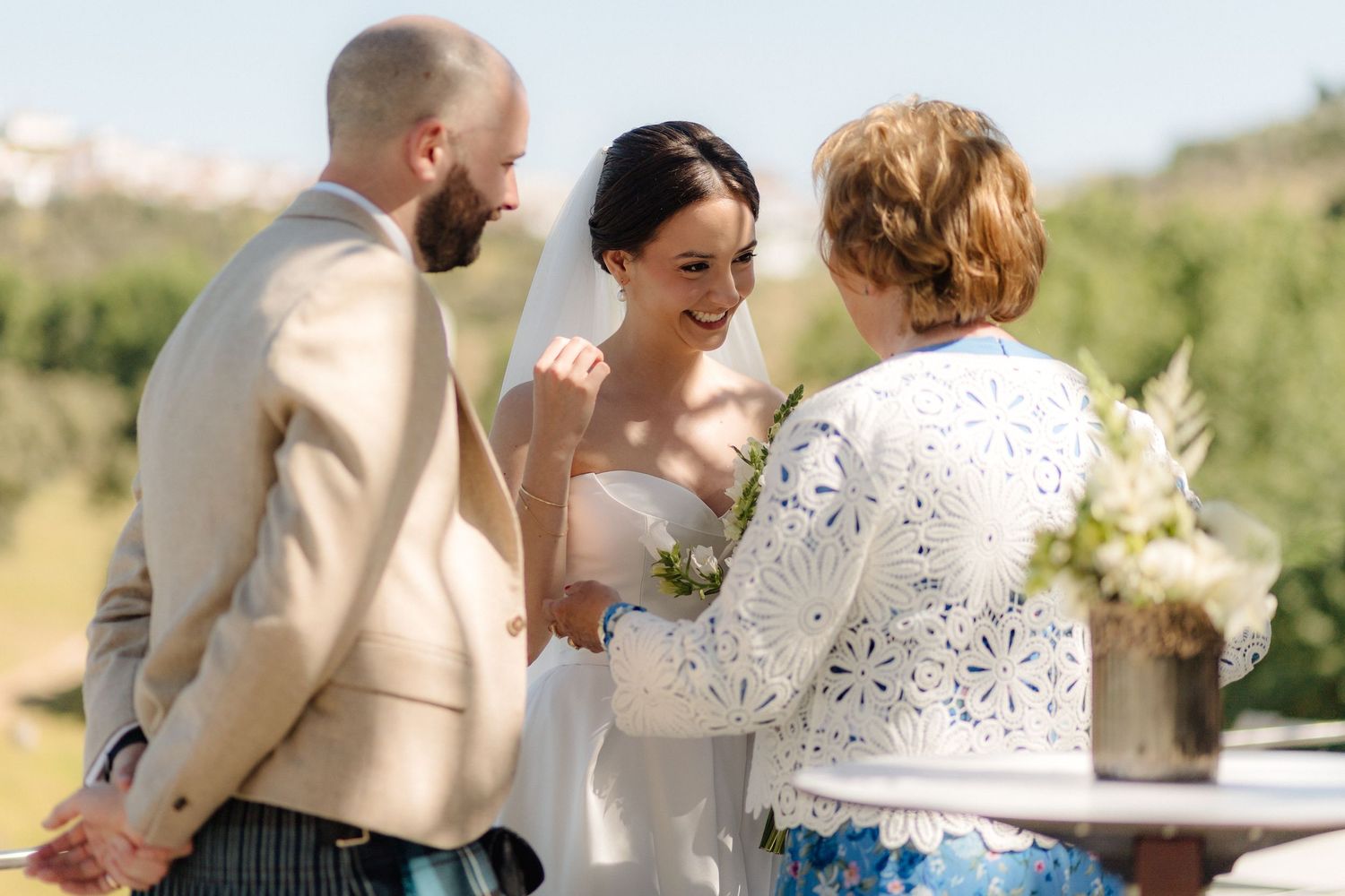 A romantic outdoor wedding ceremony takes place in a sunlit garden with elegant floral decorations.