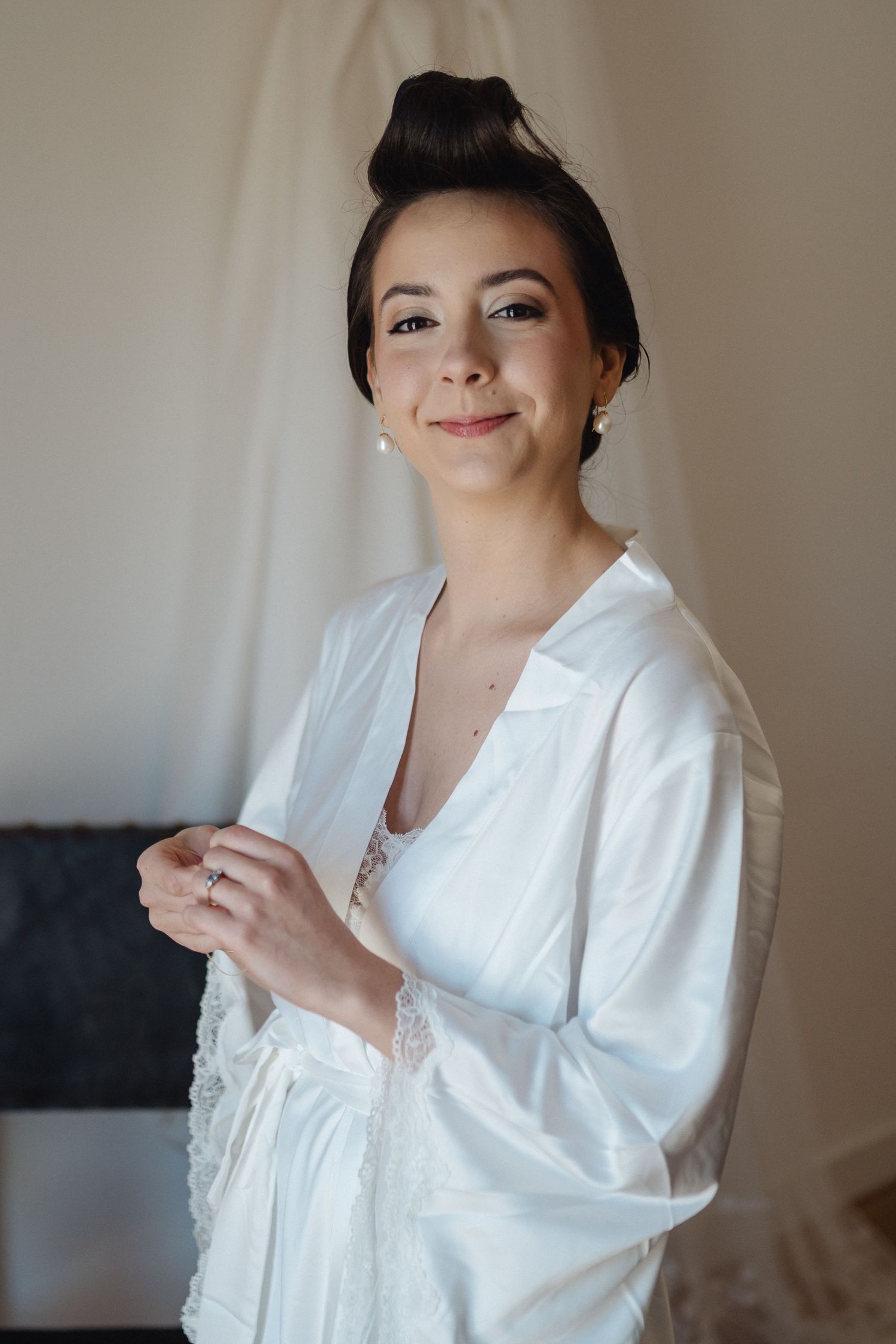 Final touches of wedding day makeup preparation in white robe.