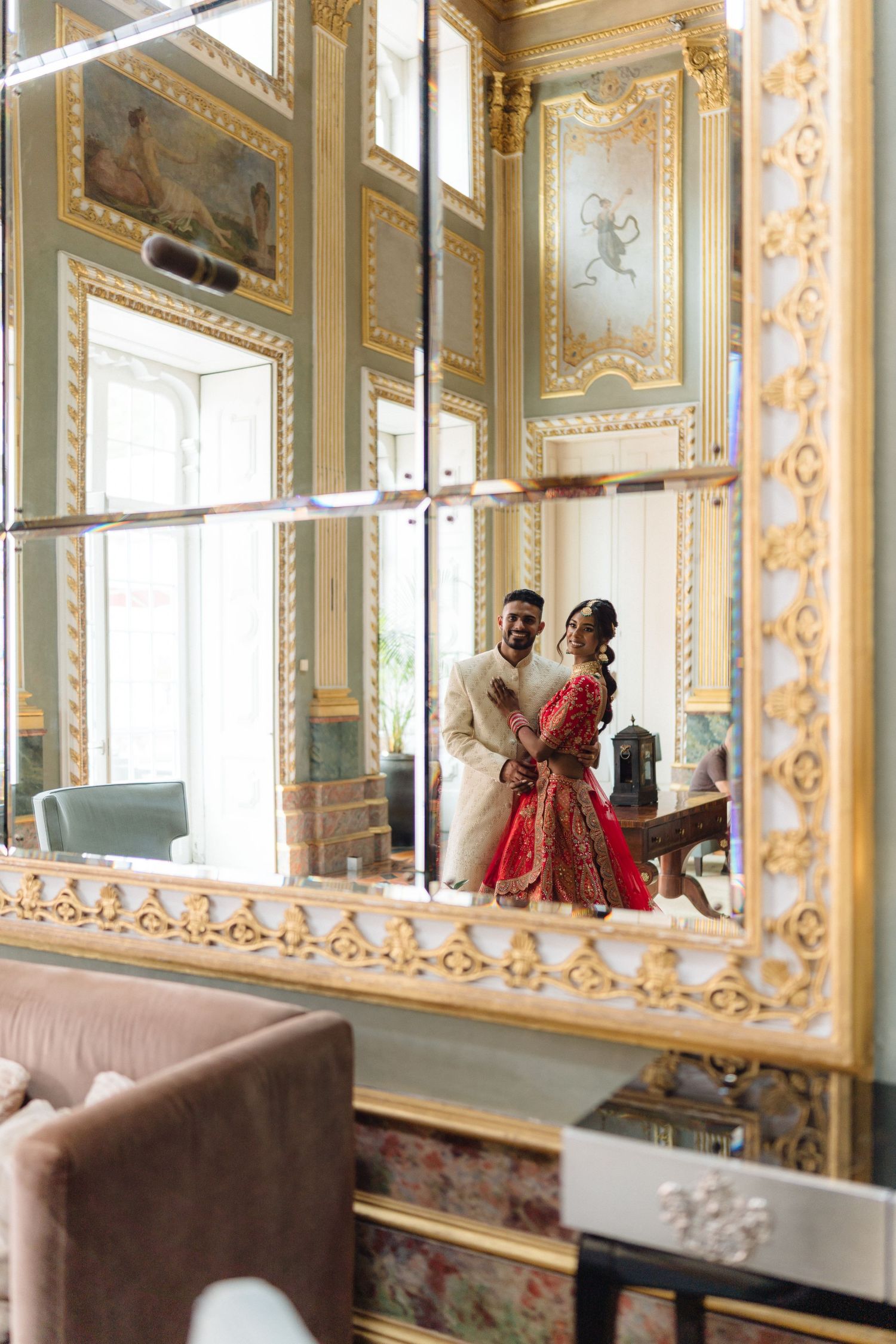 Elegant mirrored ballroom with ornate gold details and classical decor.