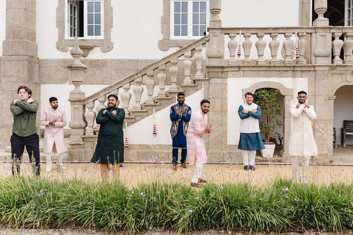 Group photo of wedding party members standing on steps of an elegant historic building.