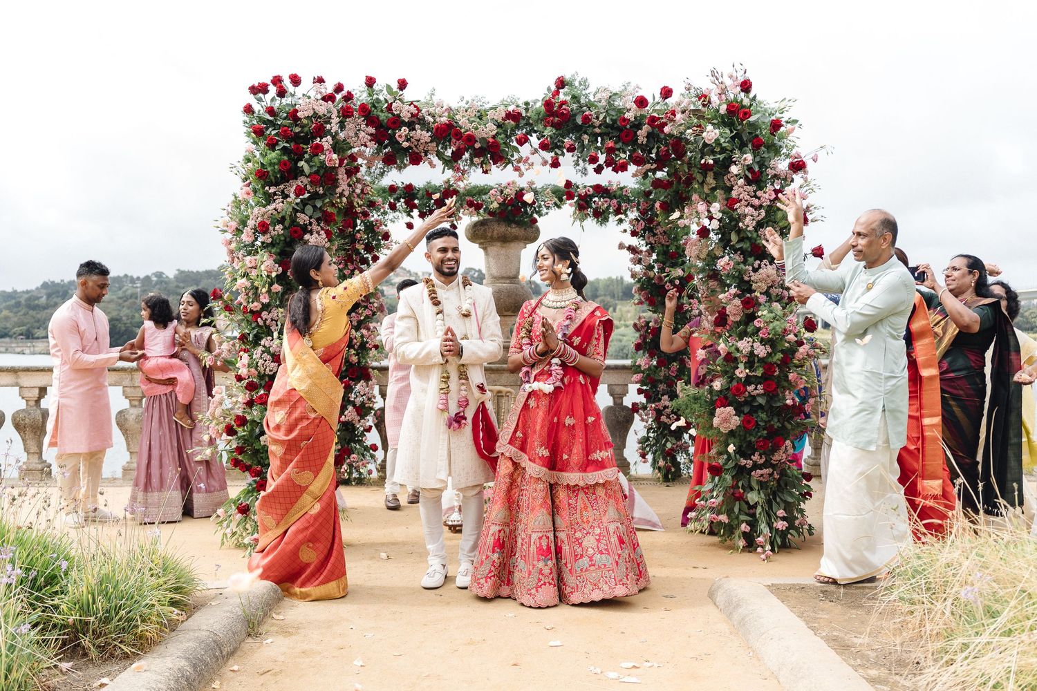 Panoramic view of an outdoor Indian wedding ceremony with red floral decorations.
