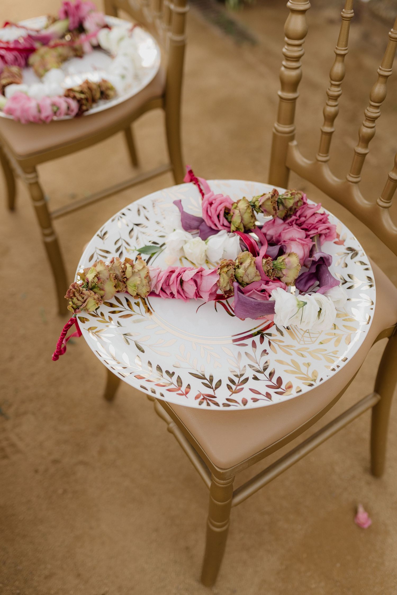 Decorative plate with pink and purple floral garland on a gold chiavari chair.