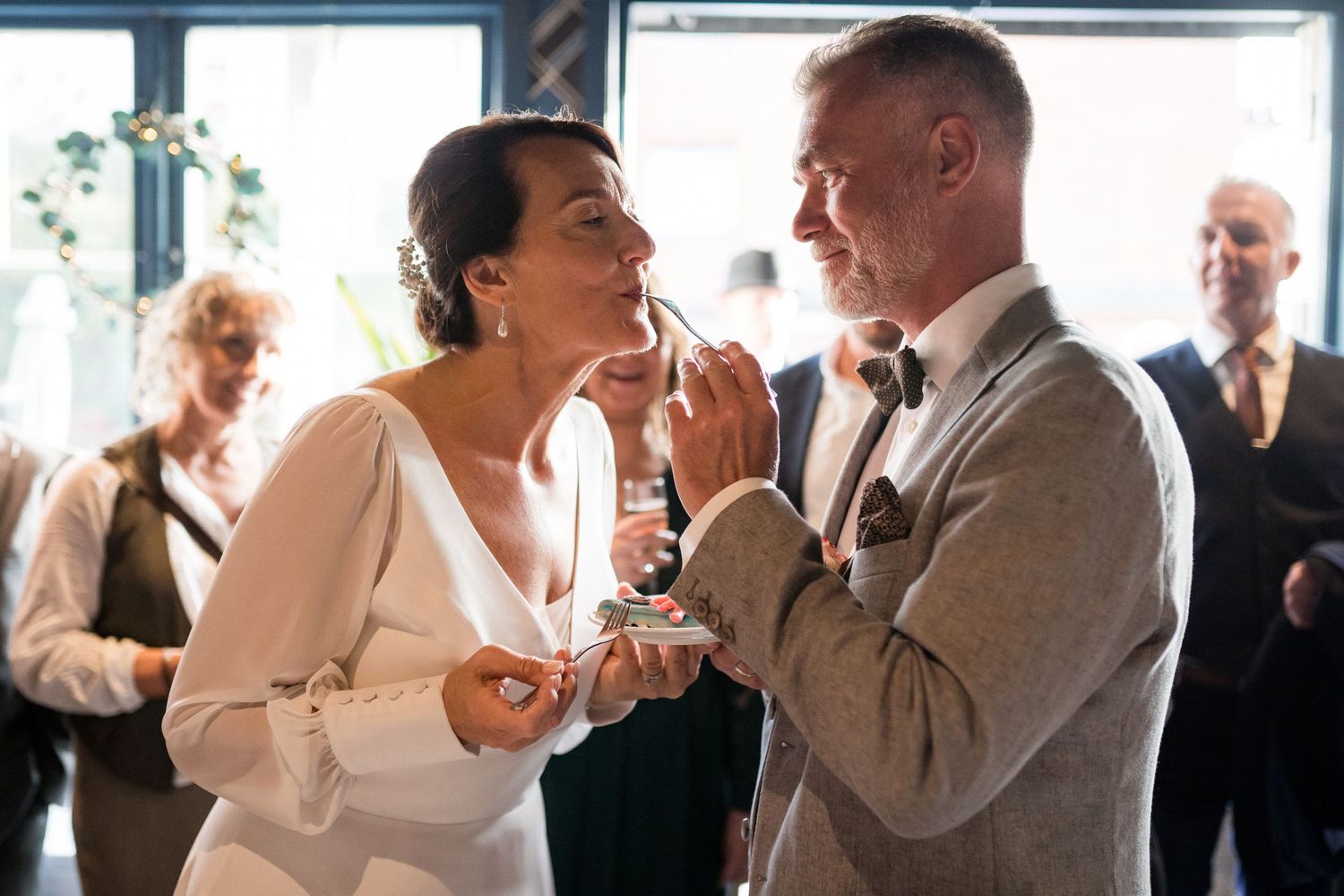 Elegantly dressed wedding guests dancing and socializing at an indoor celebration.