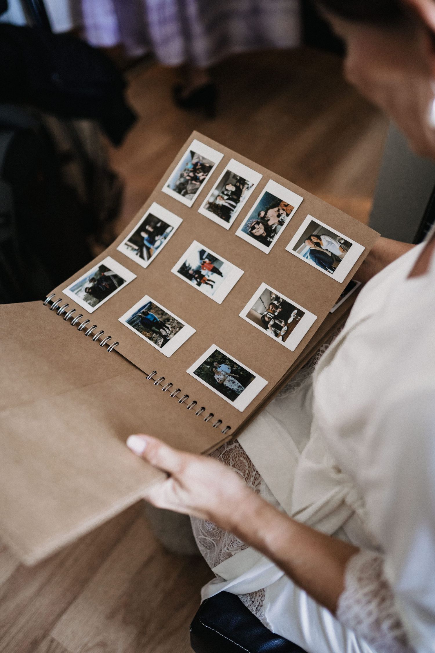 A photo album lies open on a wooden table showing polaroid style wedding photographs.