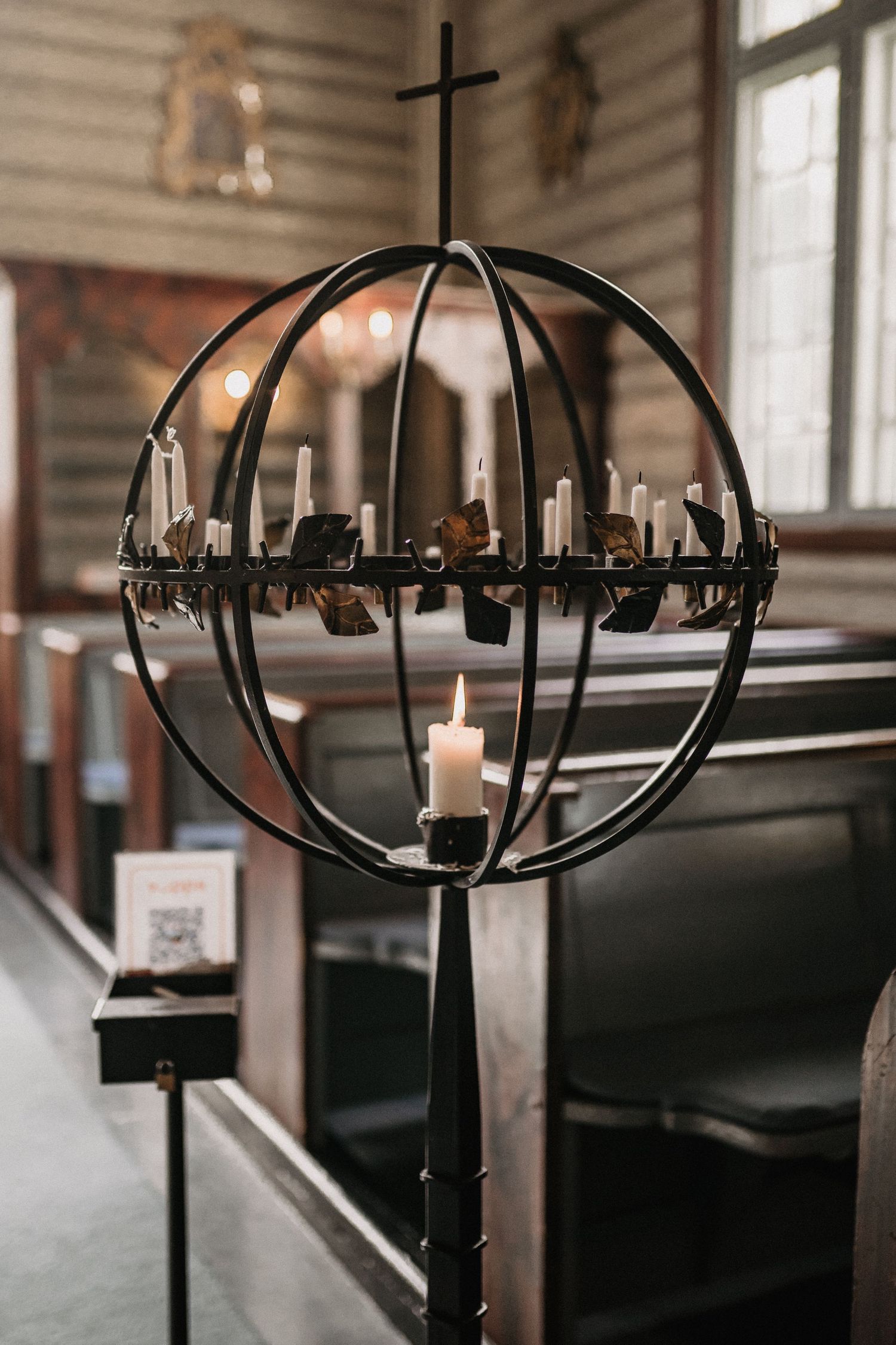 Modern spherical candle holder with cross detail in a church setting.