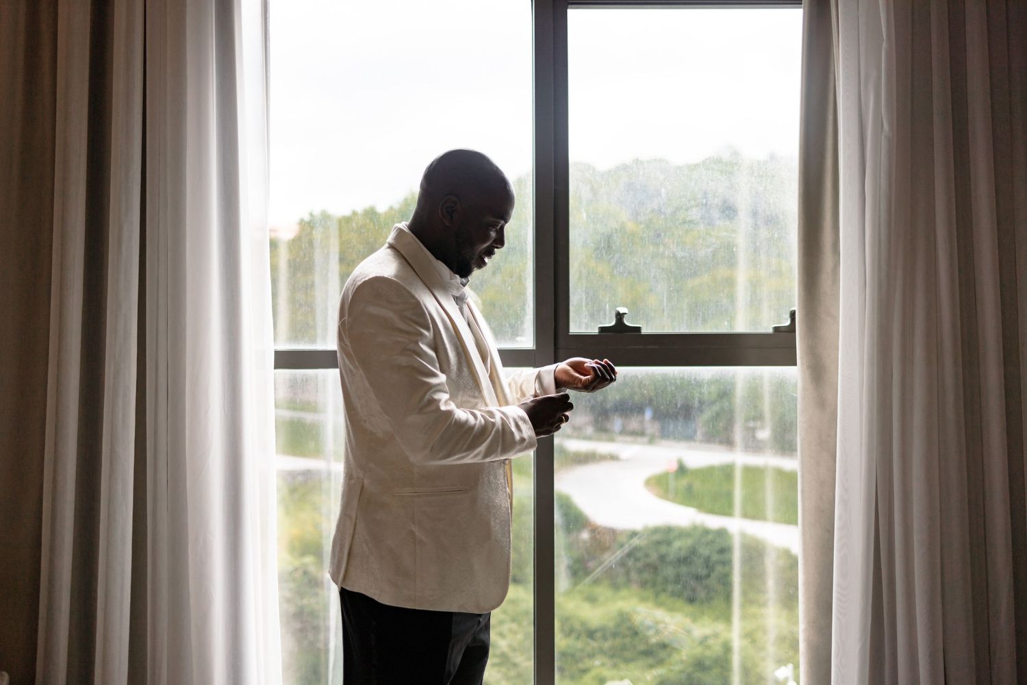 Wedding preparation scene by large windows with natural light streaming in.