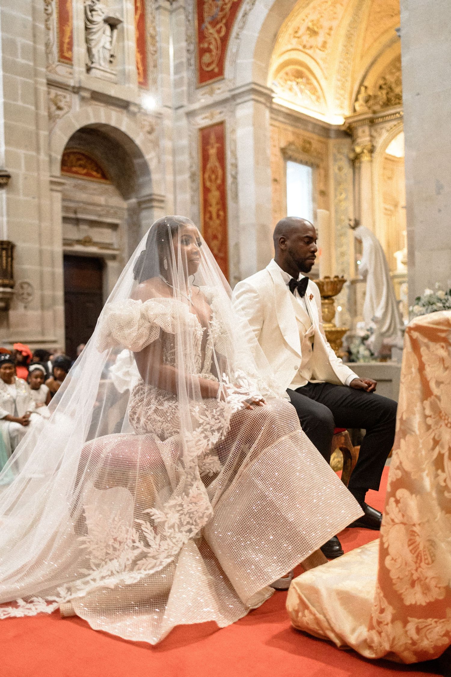 Flowing white wedding dresses with long trains displayed in an ornate church setting.
