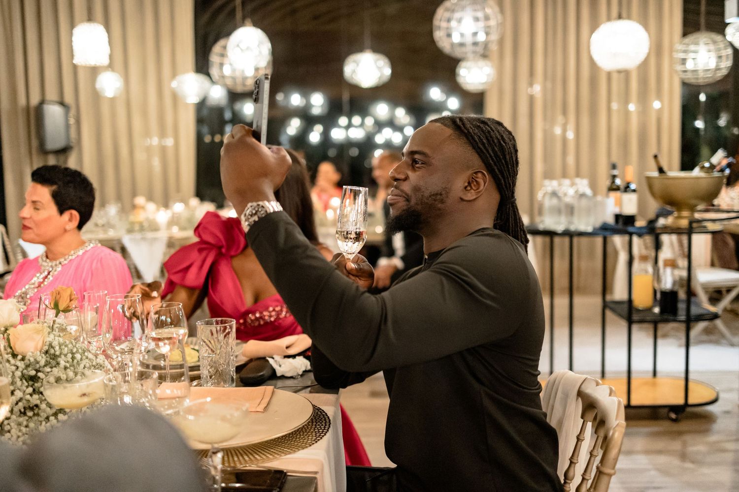 Wedding guest enjoying reception celebration under decorative ceiling lighting.