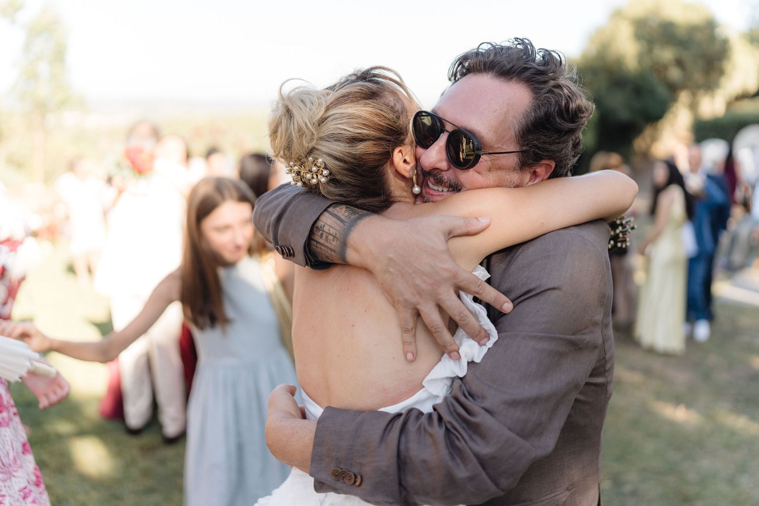Joyful embraces between wedding attendees at an outdoor garden reception.