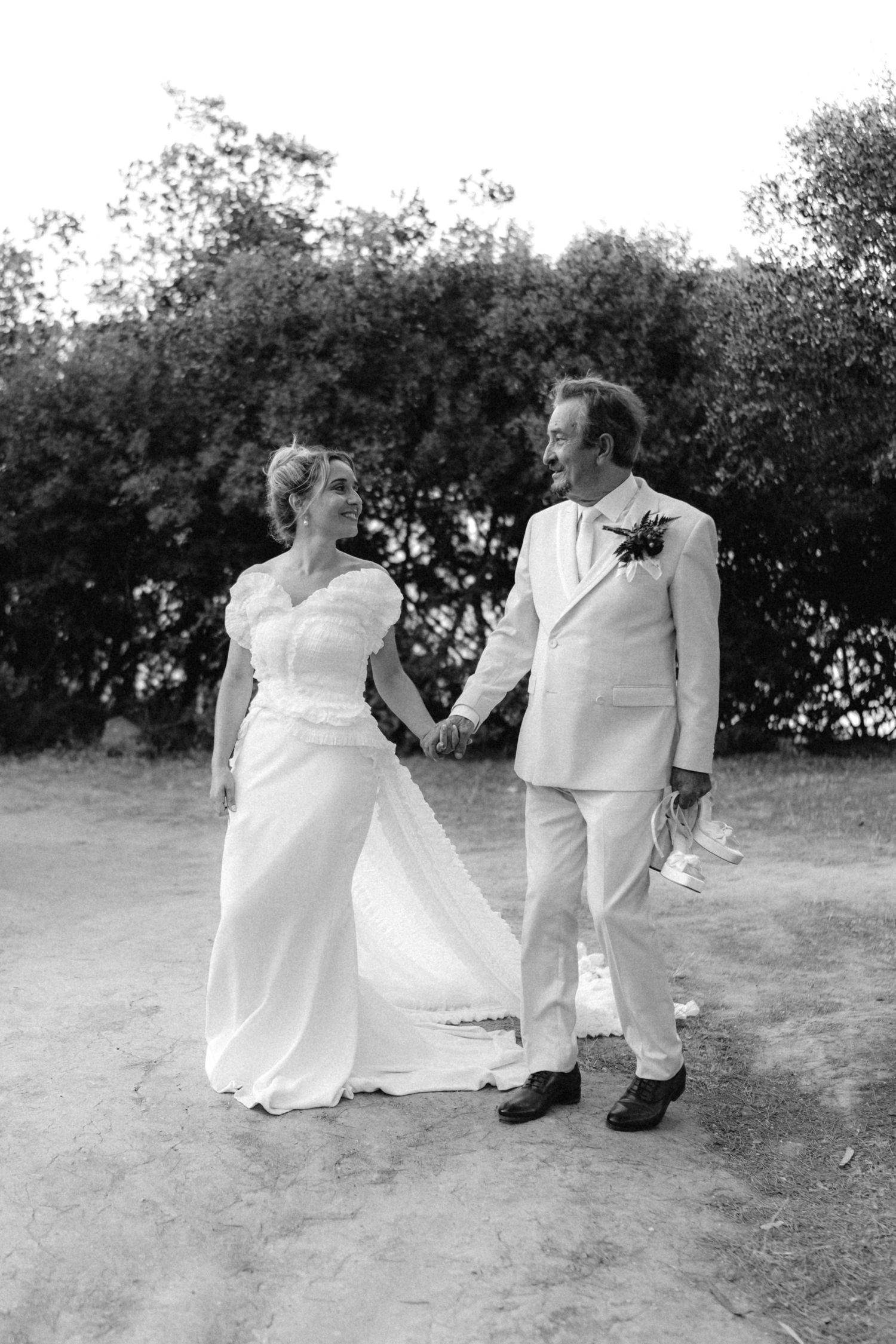 Black and white photo of newlyweds sitting together on the ground during their wedding photoshoot.