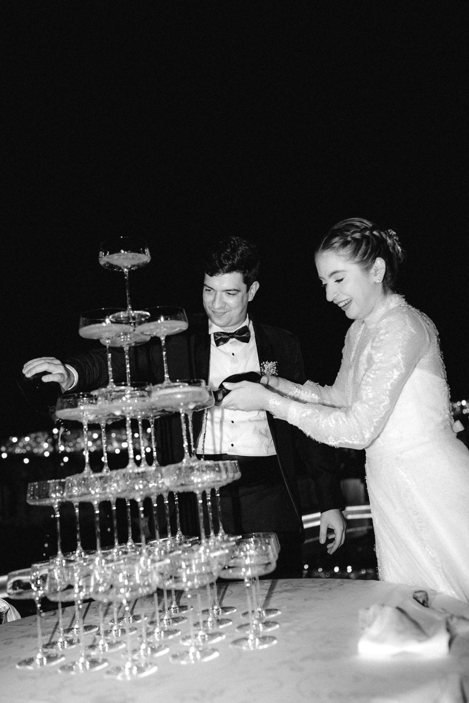 Bride and groom smiling while cutting a champagne tower at their wedding reception.