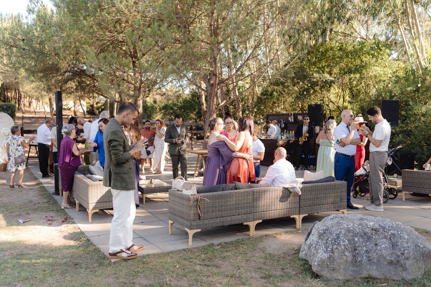 Wedding guests mingle and socialize at an outdoor reception with lounge furniture.