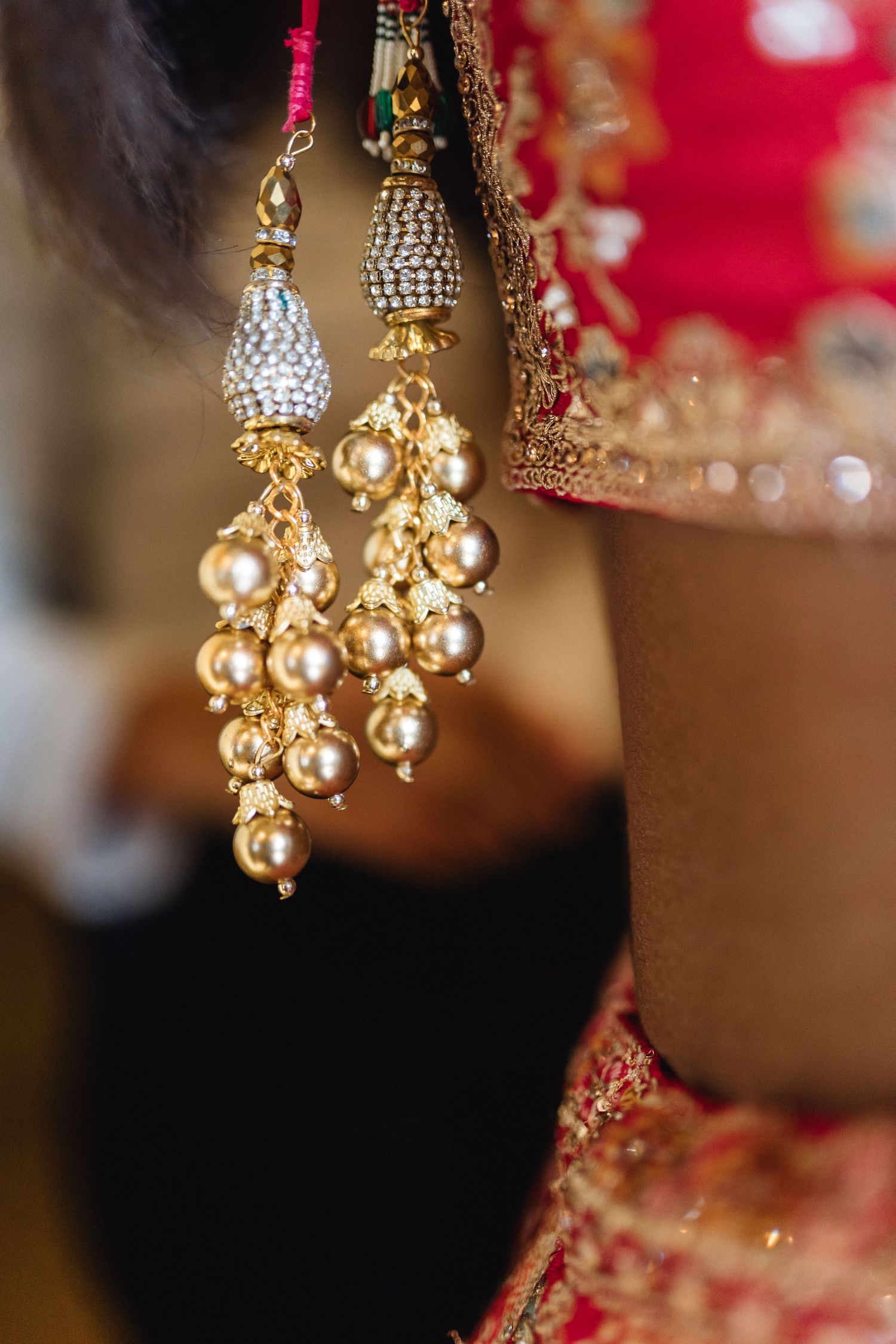 Detailed view of ornate golden Indian wedding earrings with pearl and crystal embellishments.