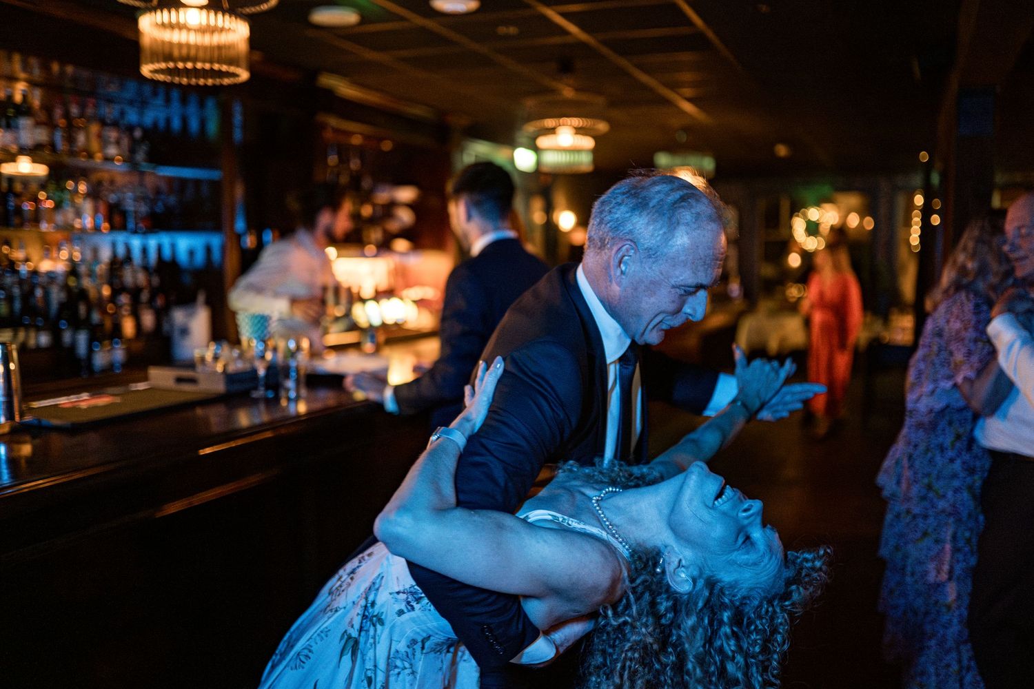 Couples dancing in a dimly lit venue with blue ambient lighting.