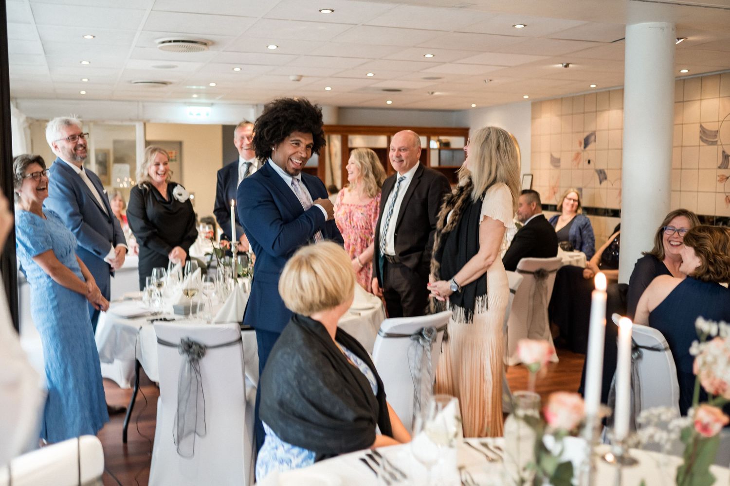 Wedding reception guests mingling in an indoor venue with elegant decor.