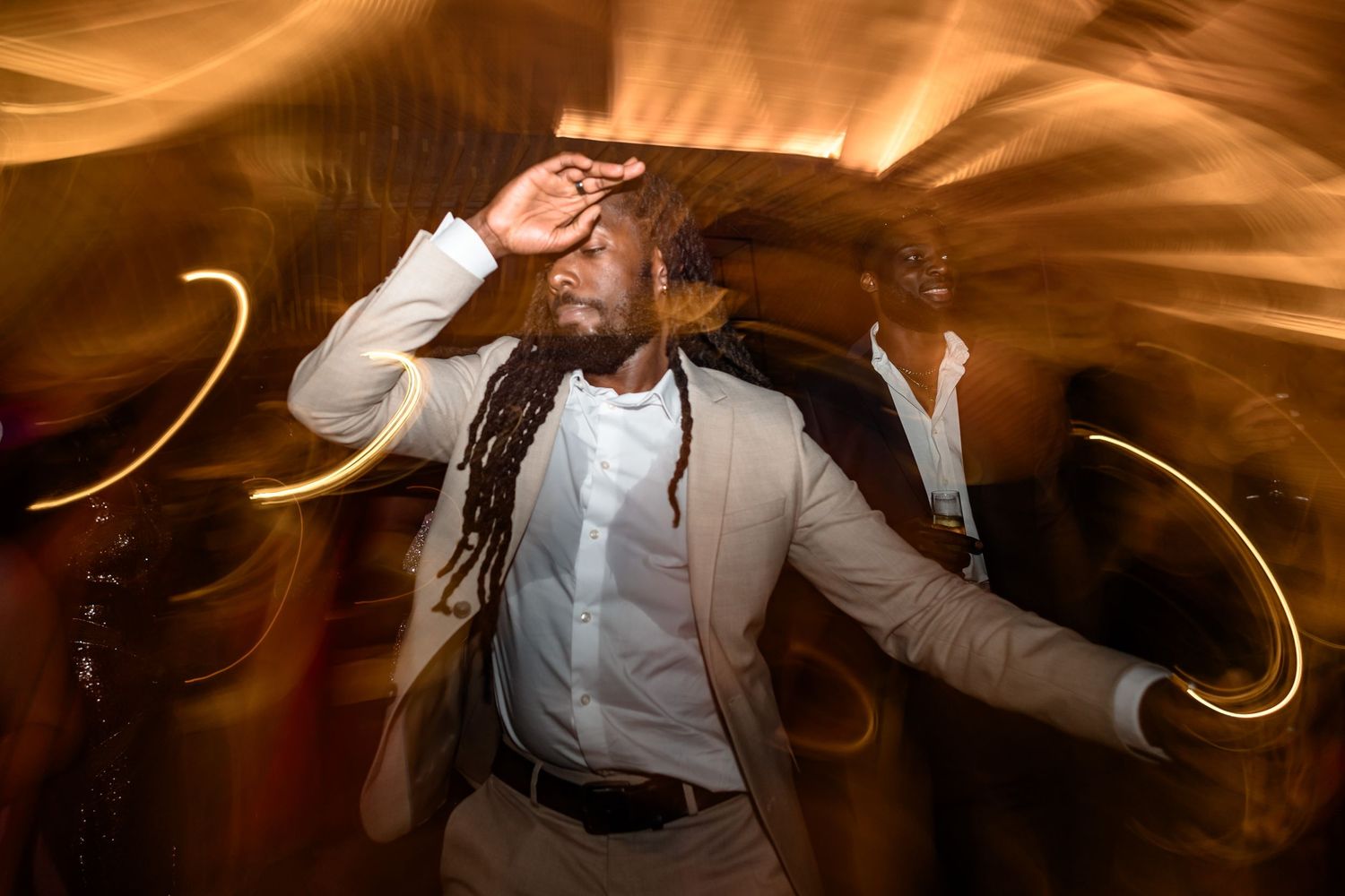 Dynamic motion shot of dancing at a celebration with warm light trails in the background.