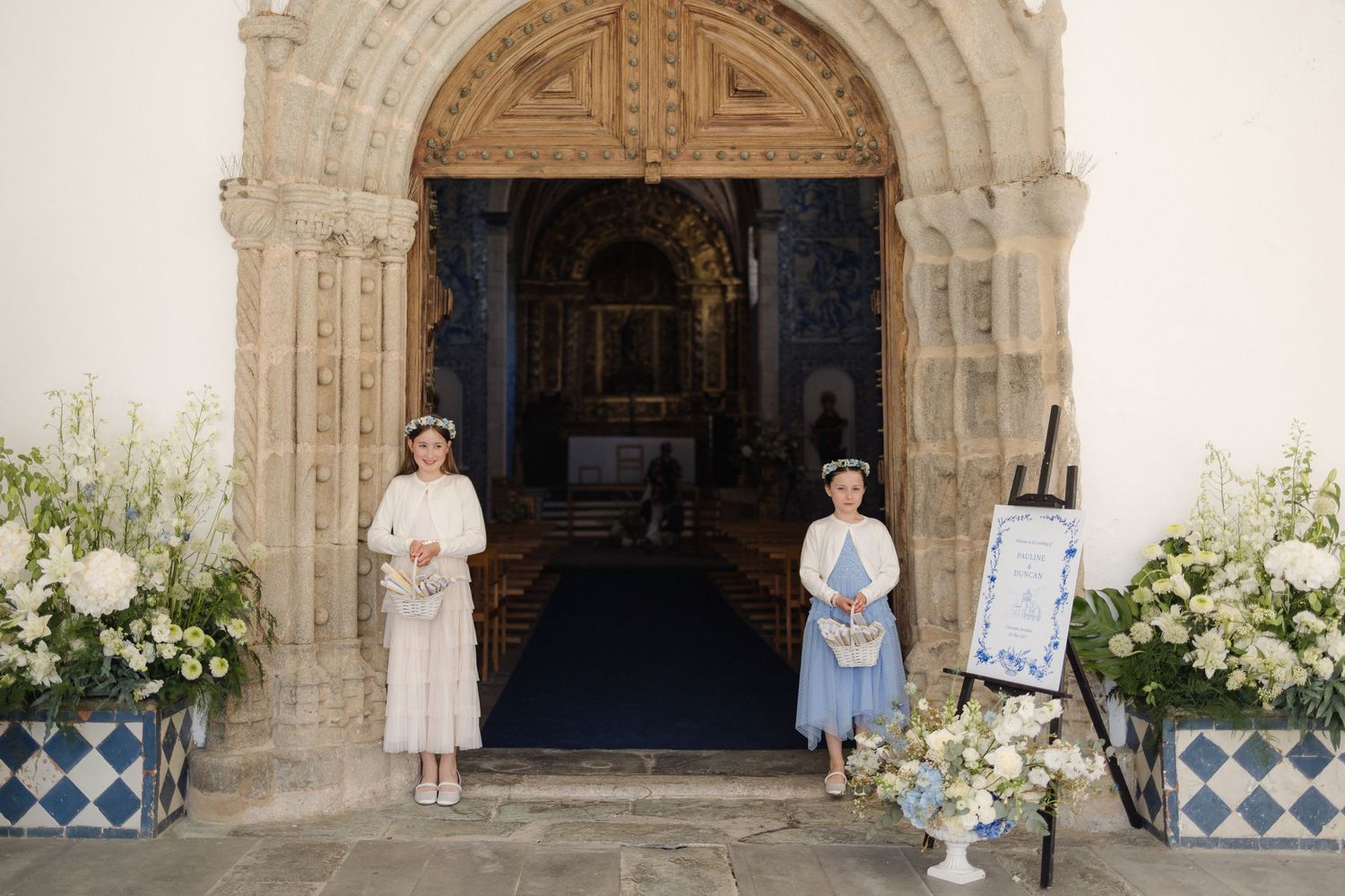 Ornate stone church entrance decorated with white floral arrangements for a wedding ceremony.