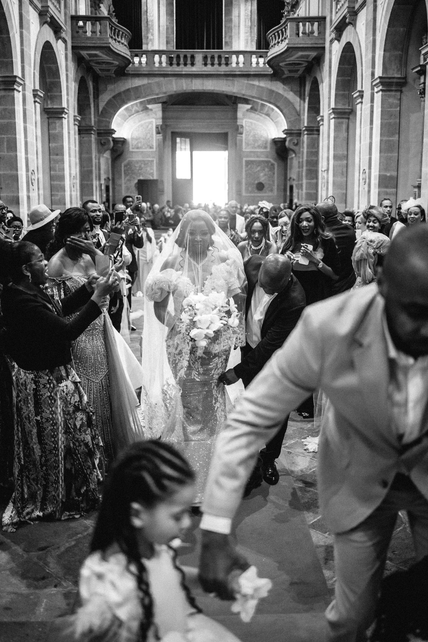 Wedding celebration with dancers in traditional attire moving through an elegant corridor.