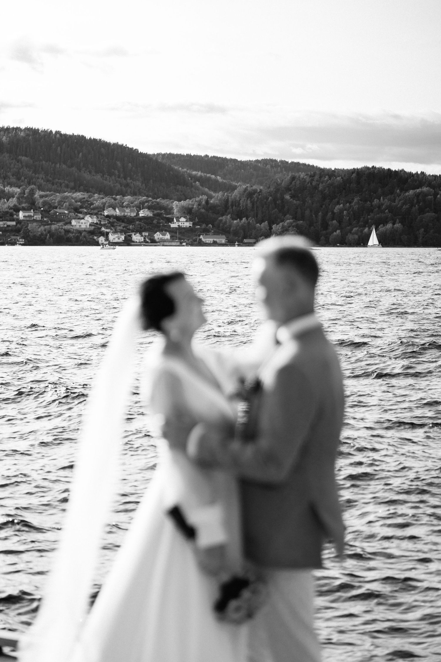 Romantic waterfront wedding photos with mountain landscape and water views in soft focus.