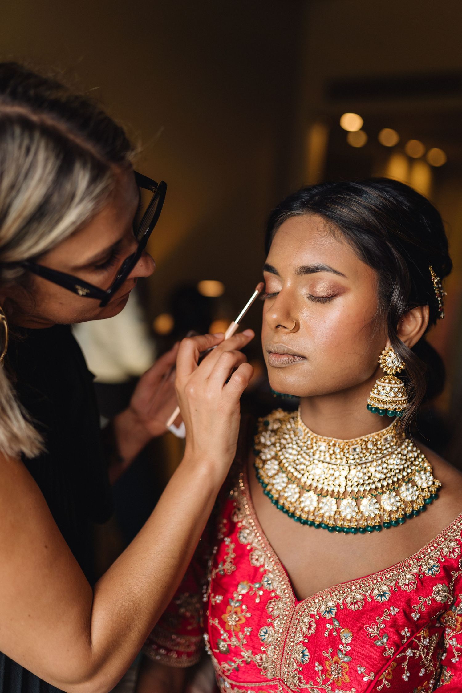 Traditional Indian bridal jewelry being applied during wedding preparations.