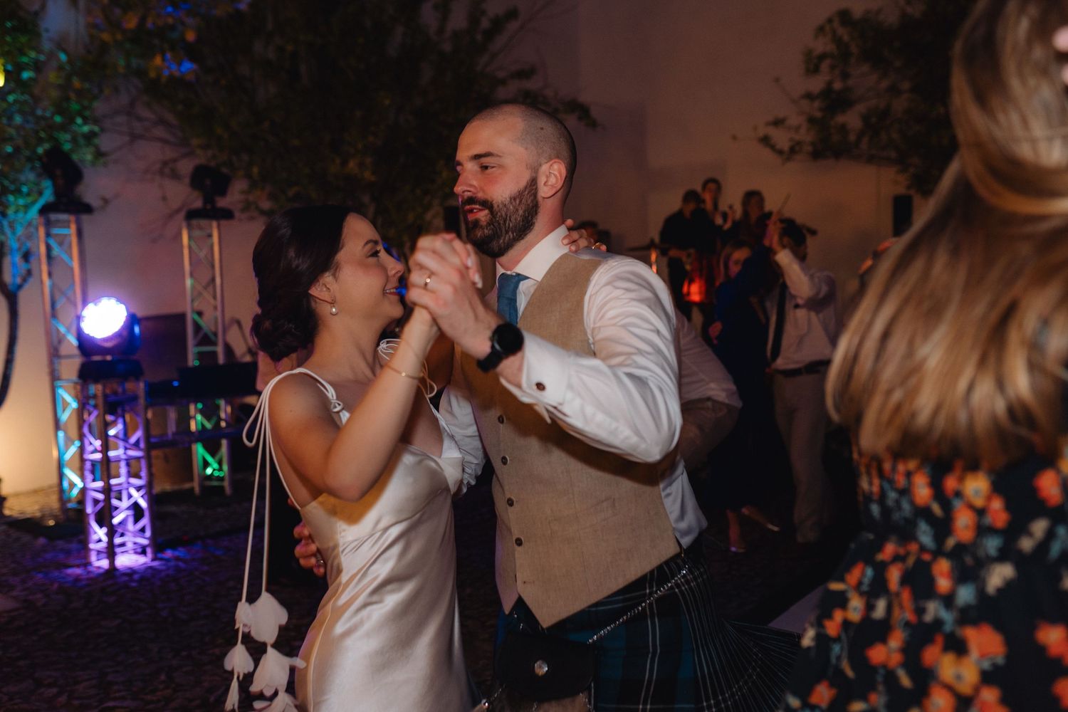 Couples dancing together at a dimly lit wedding reception with ambient lighting.
