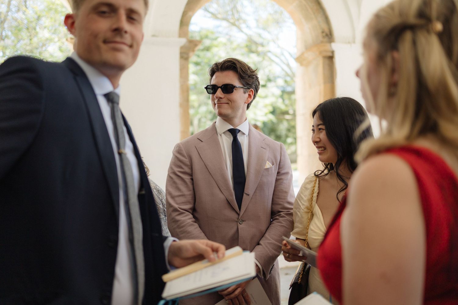 Wedding guests gathered in an elegant venue with stone archways.