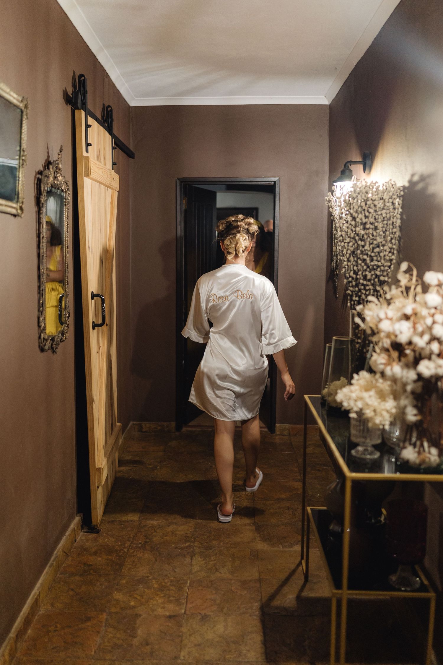 Interior hallway with white dress and floral decorations creating dramatic lighting.