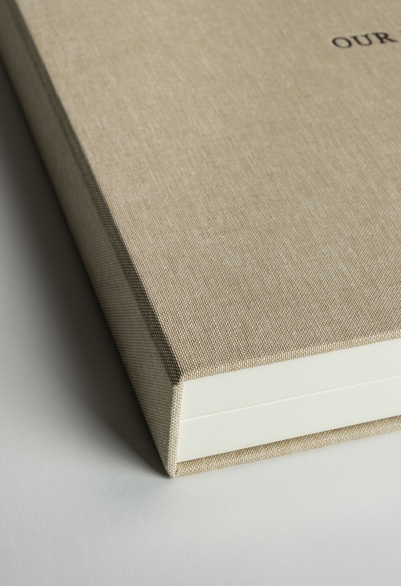 Close-up sequence showing a beige linen book spine from different angles in a minimalist style.