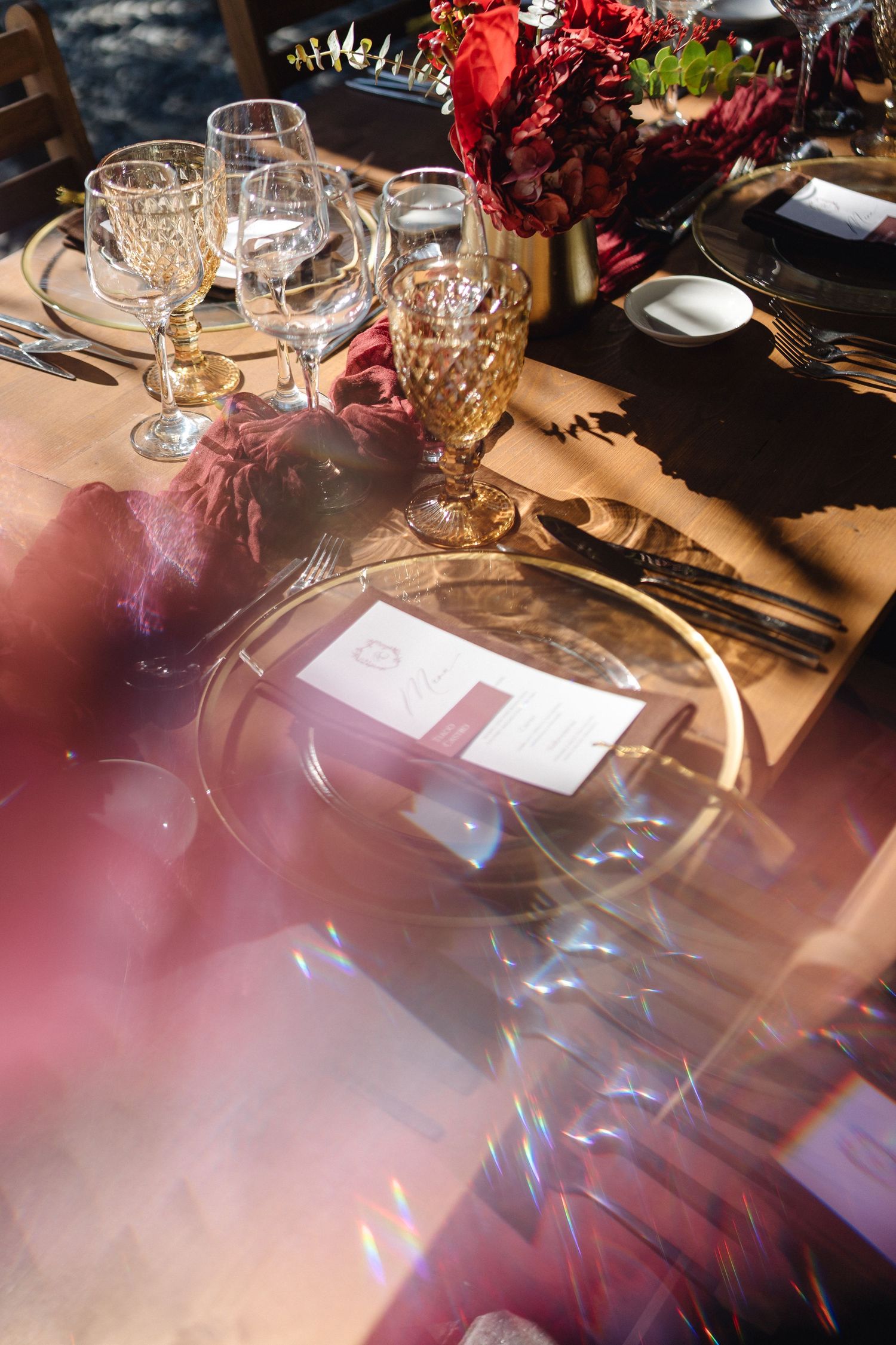 Artistic table setting with prismatic light effects and burgundy decor elements.