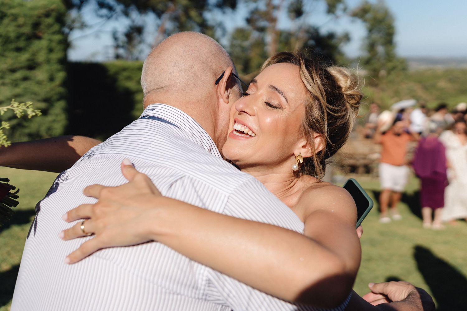 Wedding celebration with guests hugging and embracing during an outdoor summer event.