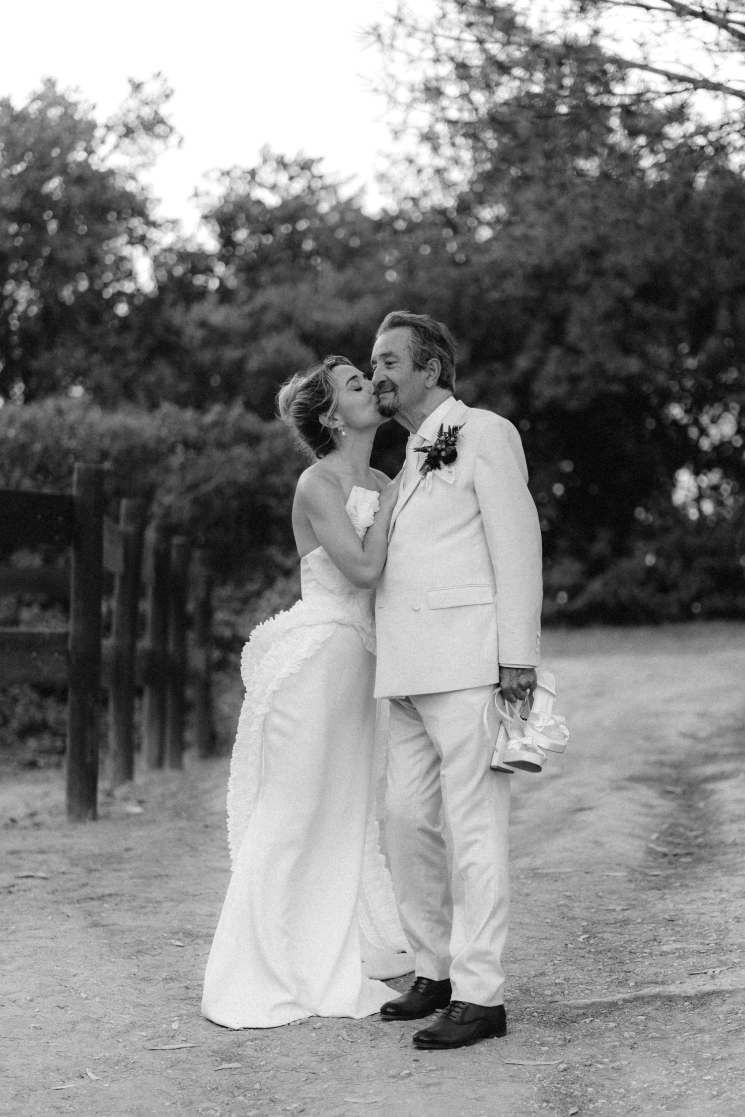 Black and white photo of newlyweds sharing romantic moment on garden path.