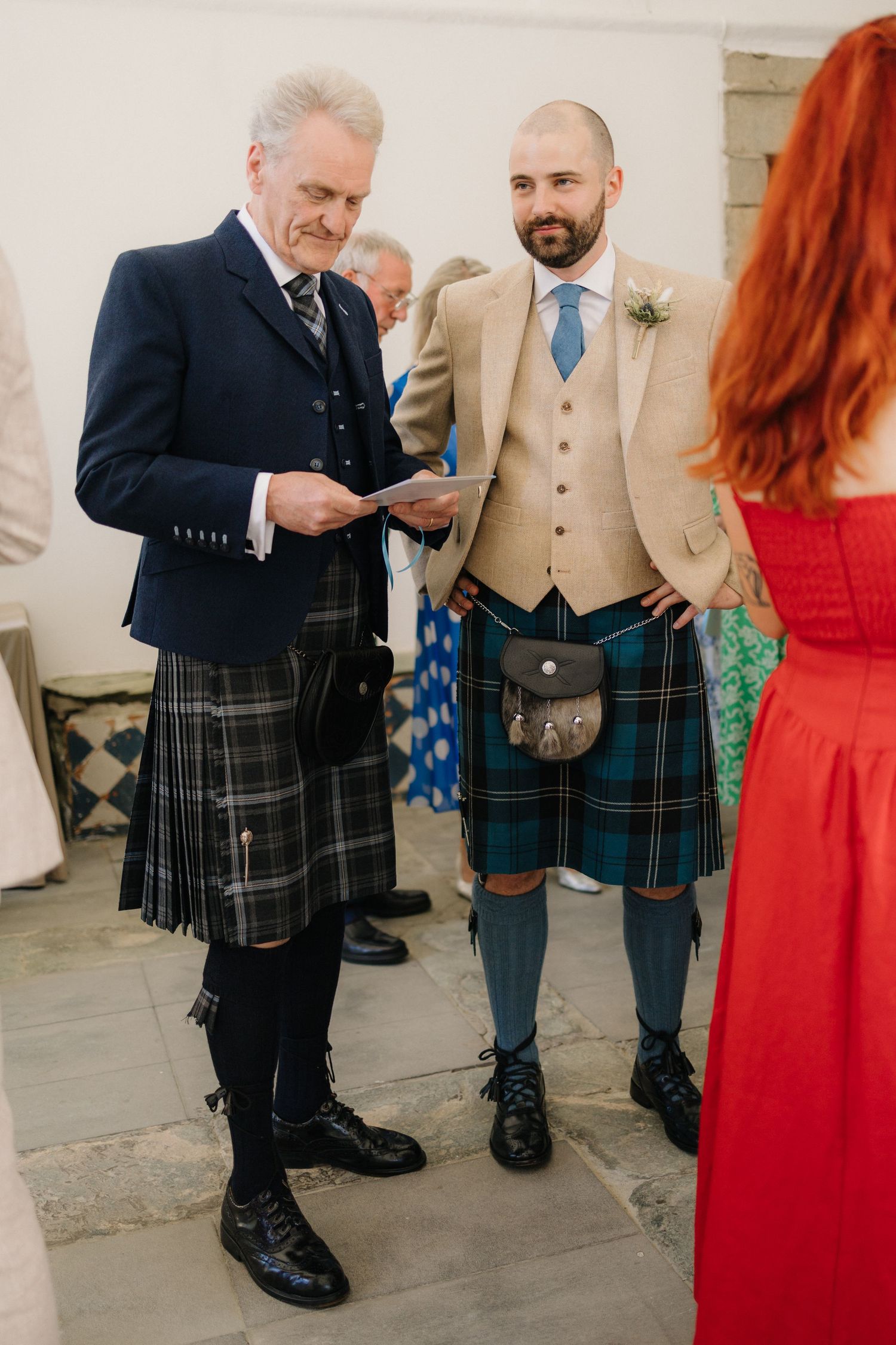 Men in traditional Scottish kilts and formal attire at a wedding celebration.