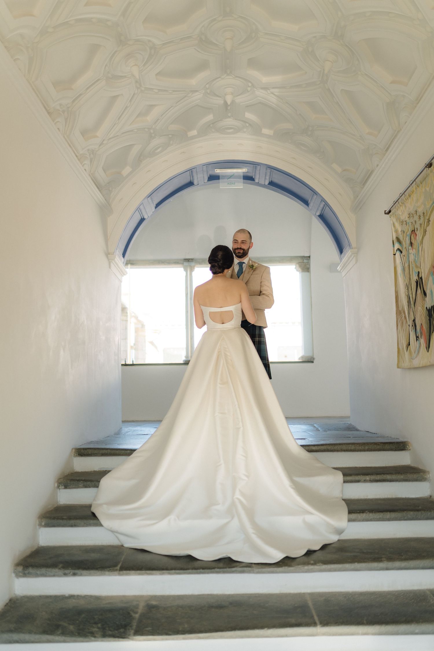 A flowing white wedding gown creates dramatic silhouettes against white arched architecture.