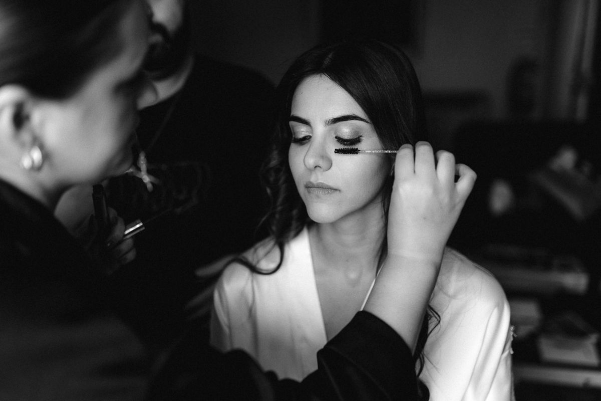 Black and white portrait of someone getting their makeup done in dramatic lighting.