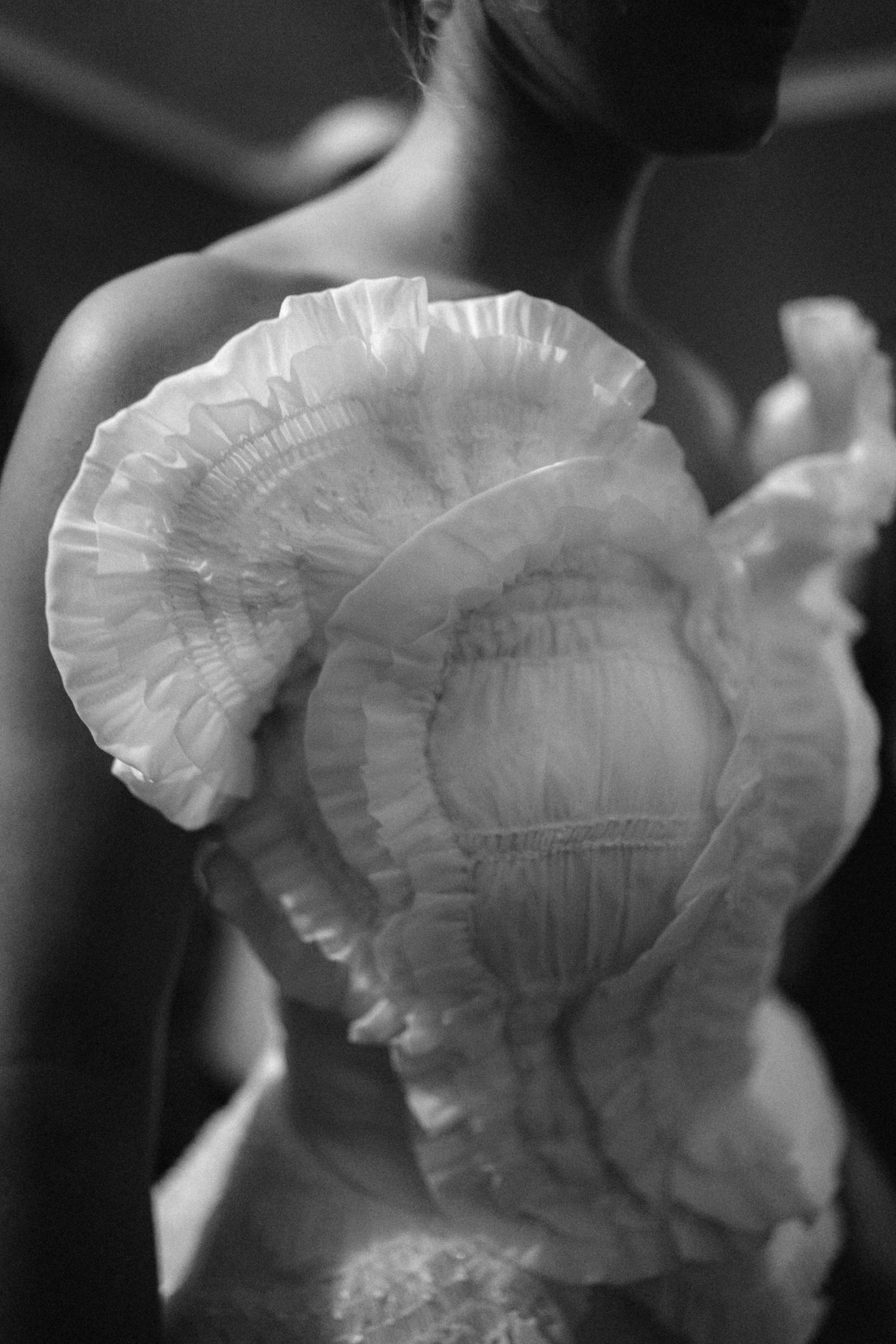 Delicate white ruffled details of wedding attire captured in black and white.