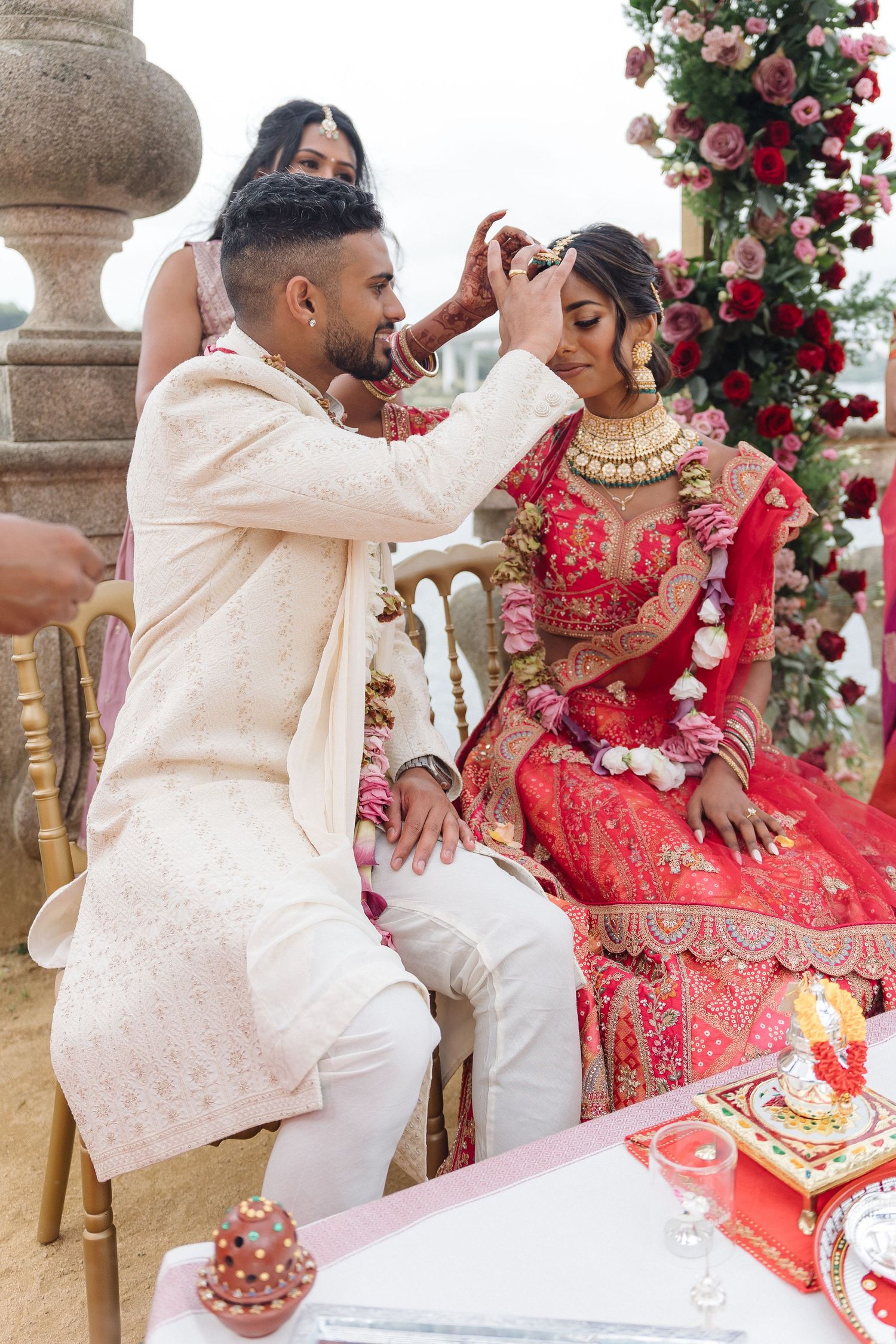Traditional Indian wedding ceremony with couple performing rituals under floral decorations.