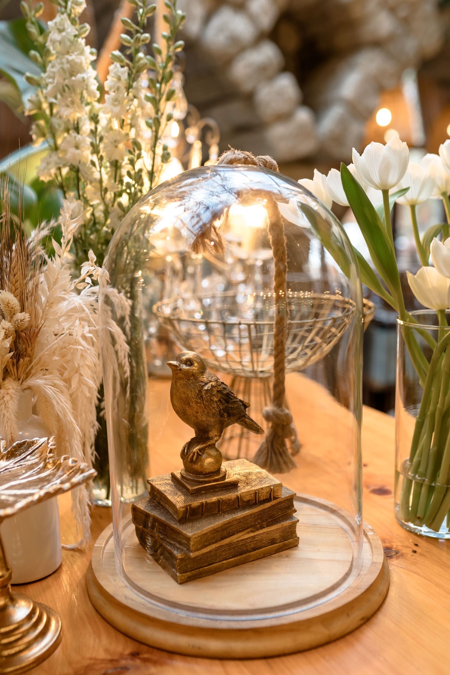 Elegant table settings with glass domes, white feathers, and candlelight create a romantic wedding reception atmosphere.