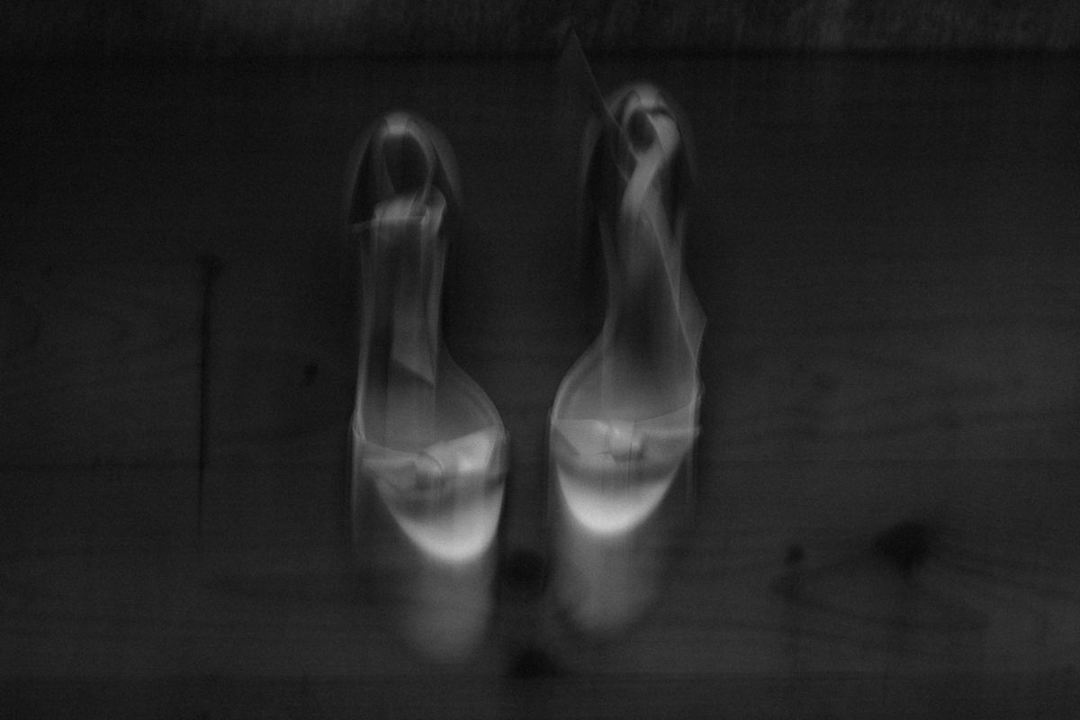 Artistic black and white composition of wedding shoes in shadow.