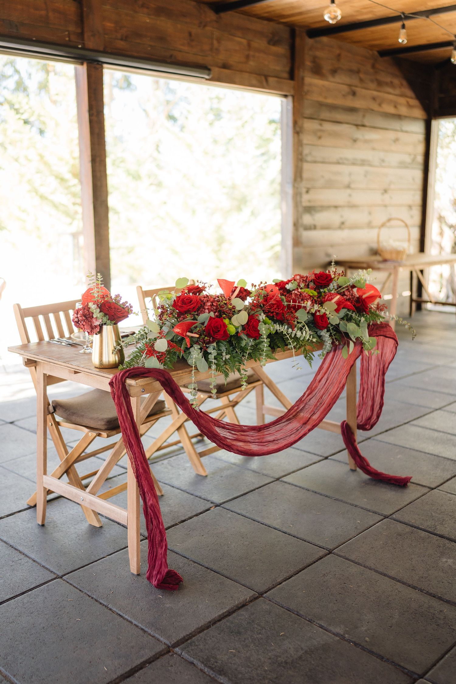 Wedding ceremony chairs decorated with burgundy fabric and floral arrangements in an outdoor venue.