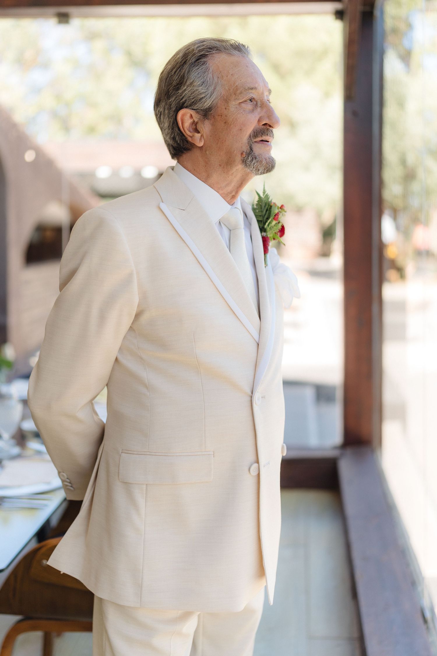 Person wearing a crisp white suit jacket smiling in an elegant indoor setting.