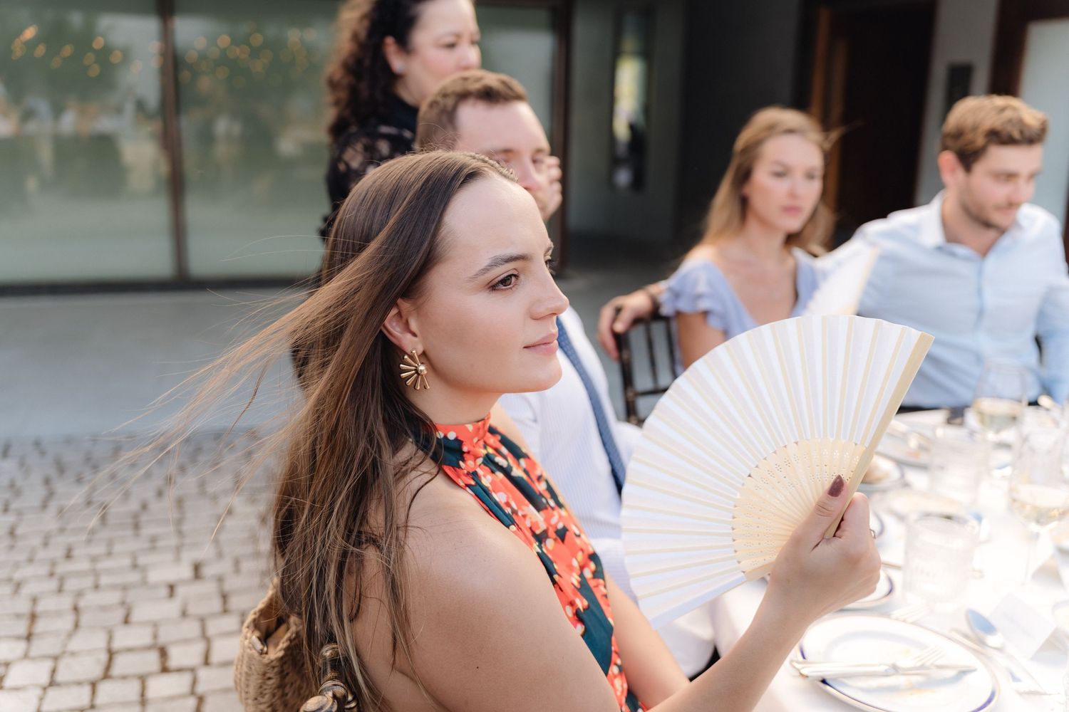 Guests seated at an elegant outdoor dining table during a daytime celebration.